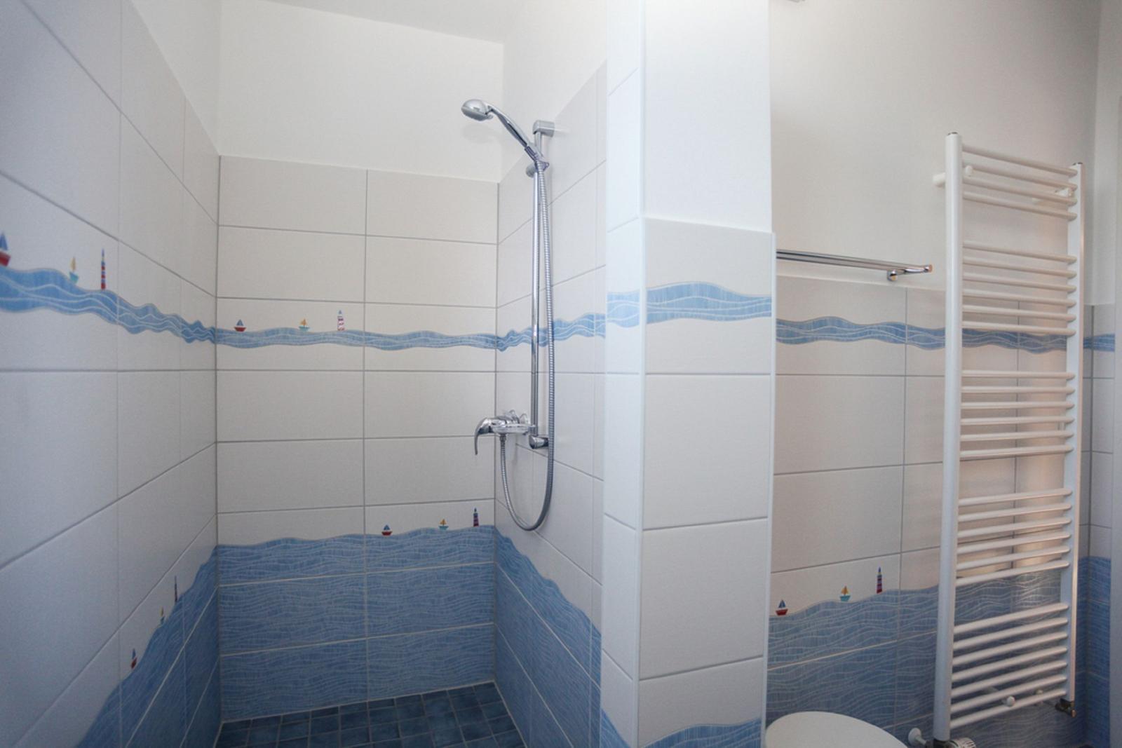 Dusche mit blauen Fliesen und Schiffsmotiven an den Wänden.