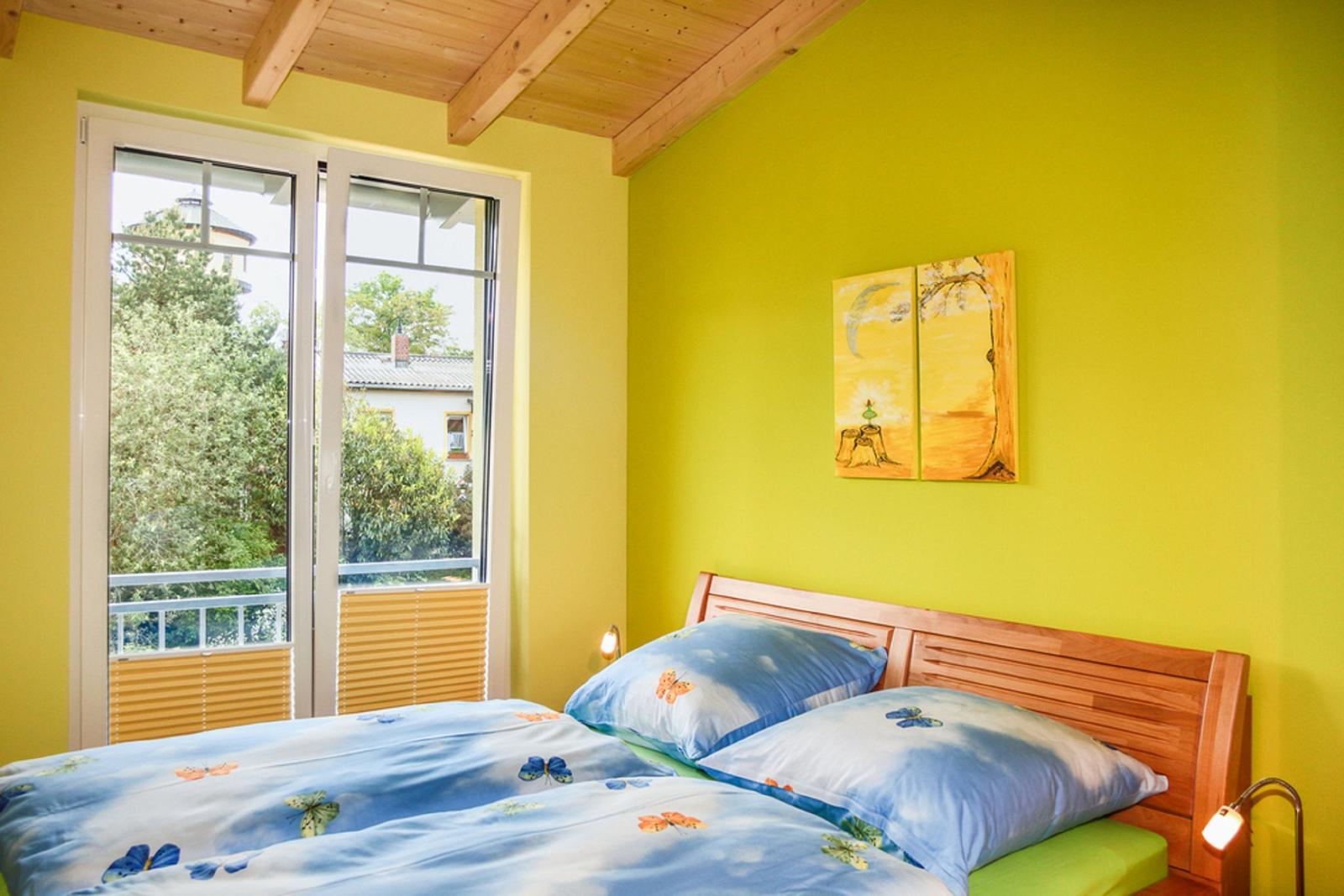 Ein Schlafzimmer mit gelben Wänden, Holzdecke und einem Bett mit Schmetterlingsmotiv.