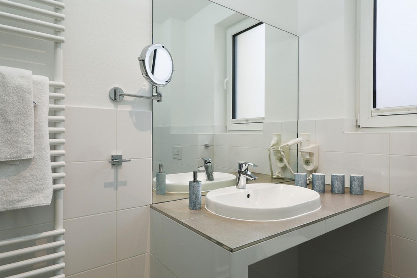 Badezimmer mit Waschbecken, Spiegel und Handtuchheizung.