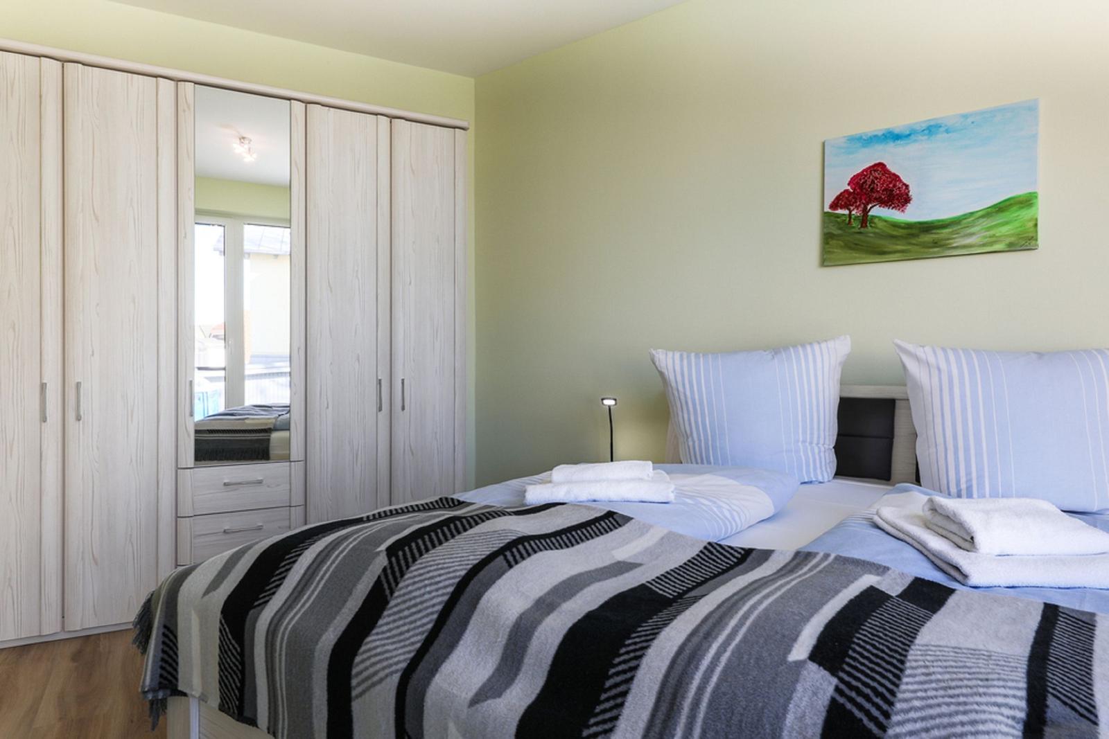 Schlafzimmer mit Doppelbett, Kleiderschrank und Wandbild.