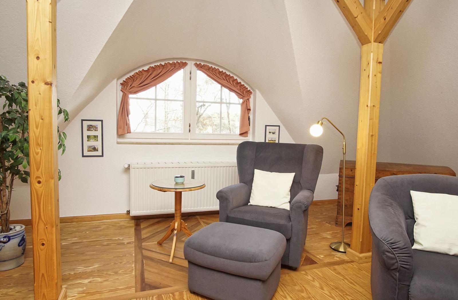 Dachgeschosszimmer mit Sessel, Fußhocker und Fenster