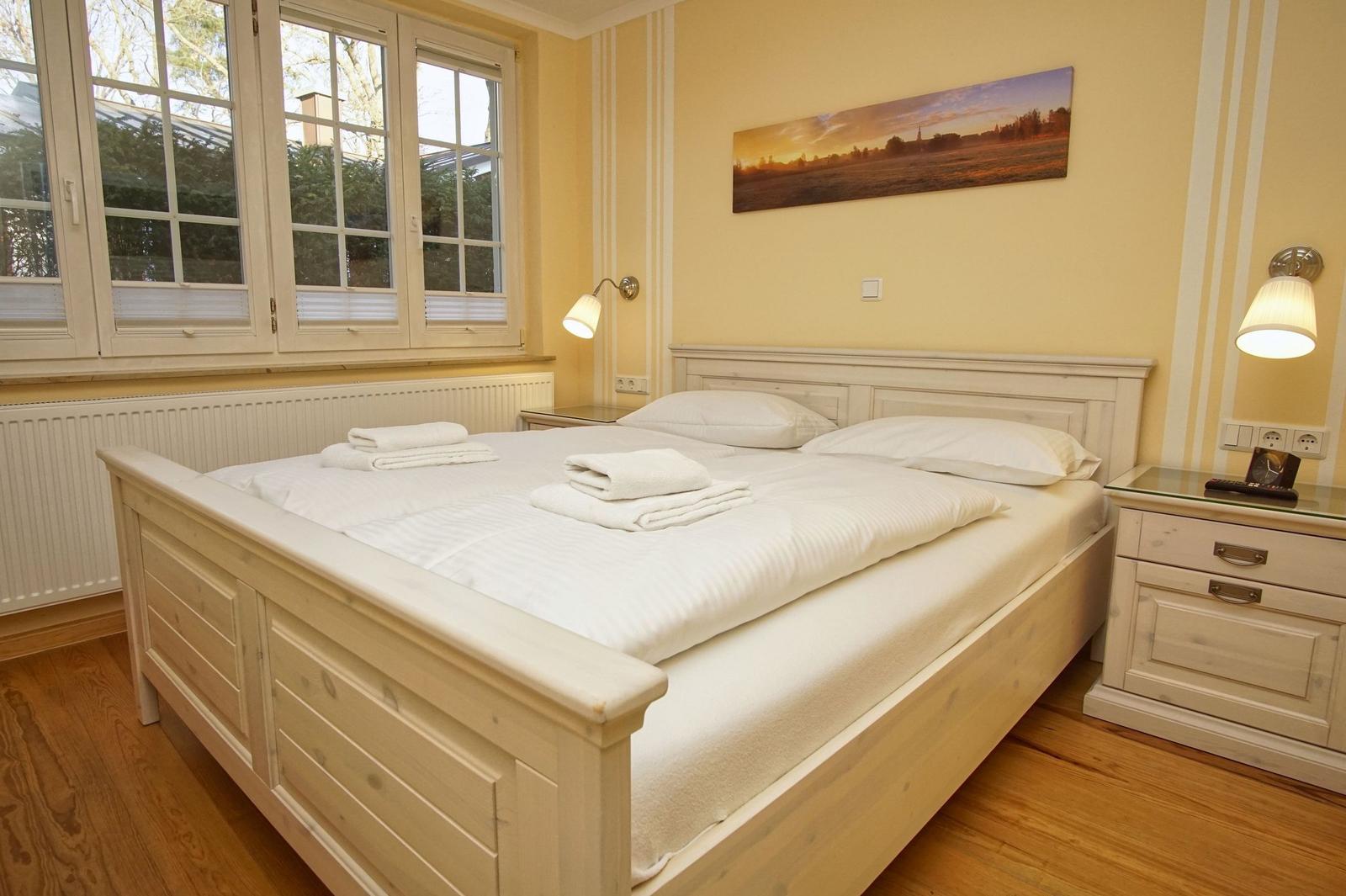 Schlafzimmer mit Doppelbett, Fenstern und Nachttisch