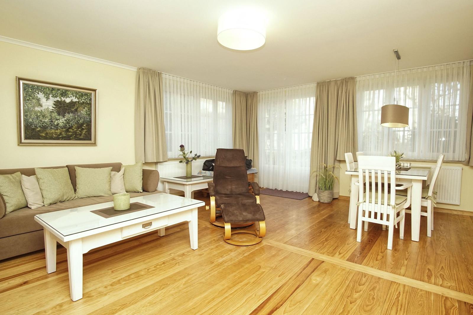 Wohn- und Essbereich mit Holzboden, Sofa, Esstisch und Sessel.