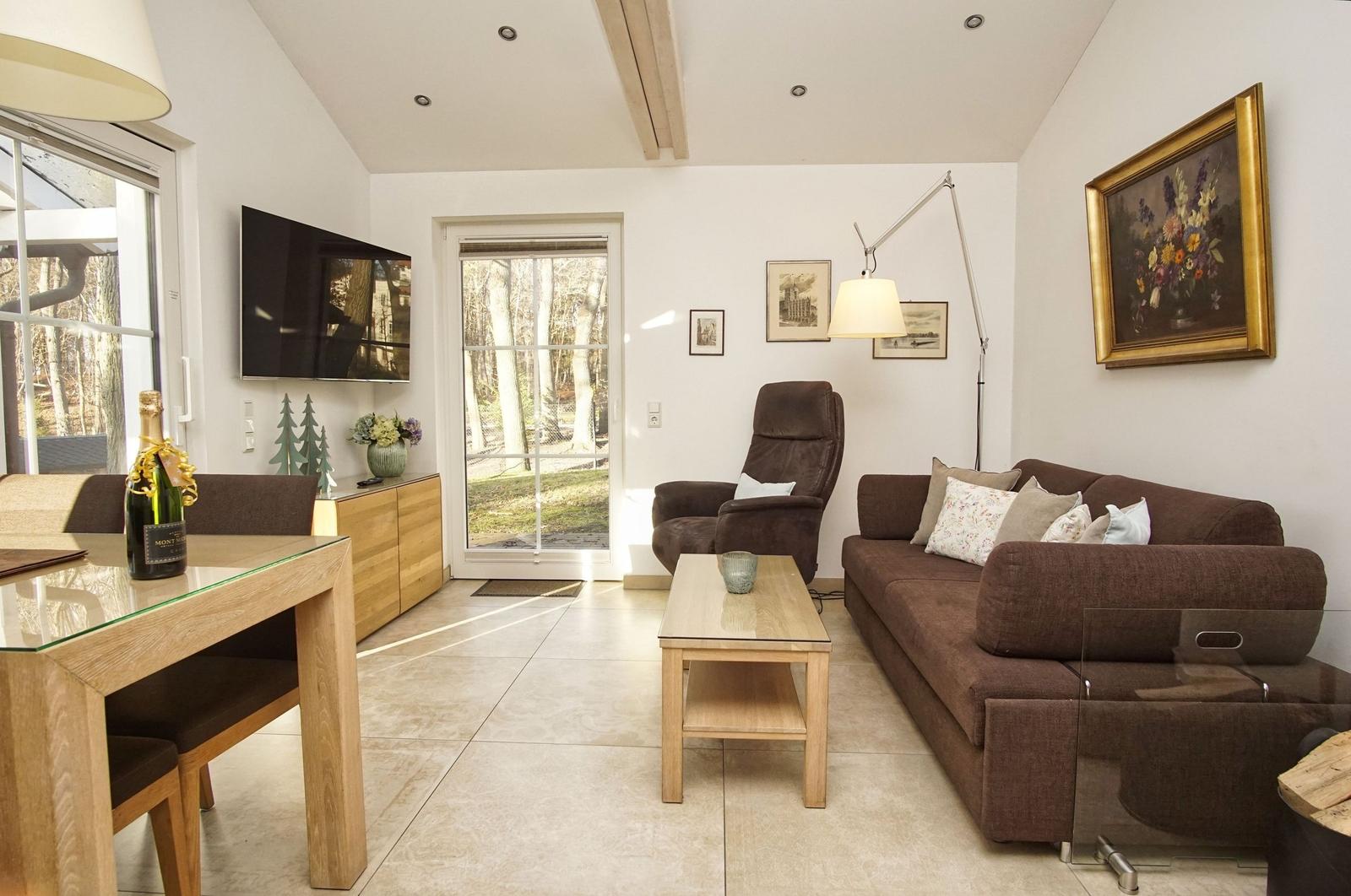 Wohn- und Essbereich mit Sofa, Sessel, Couchtisch und TV. Durchgang zur Terrasse.