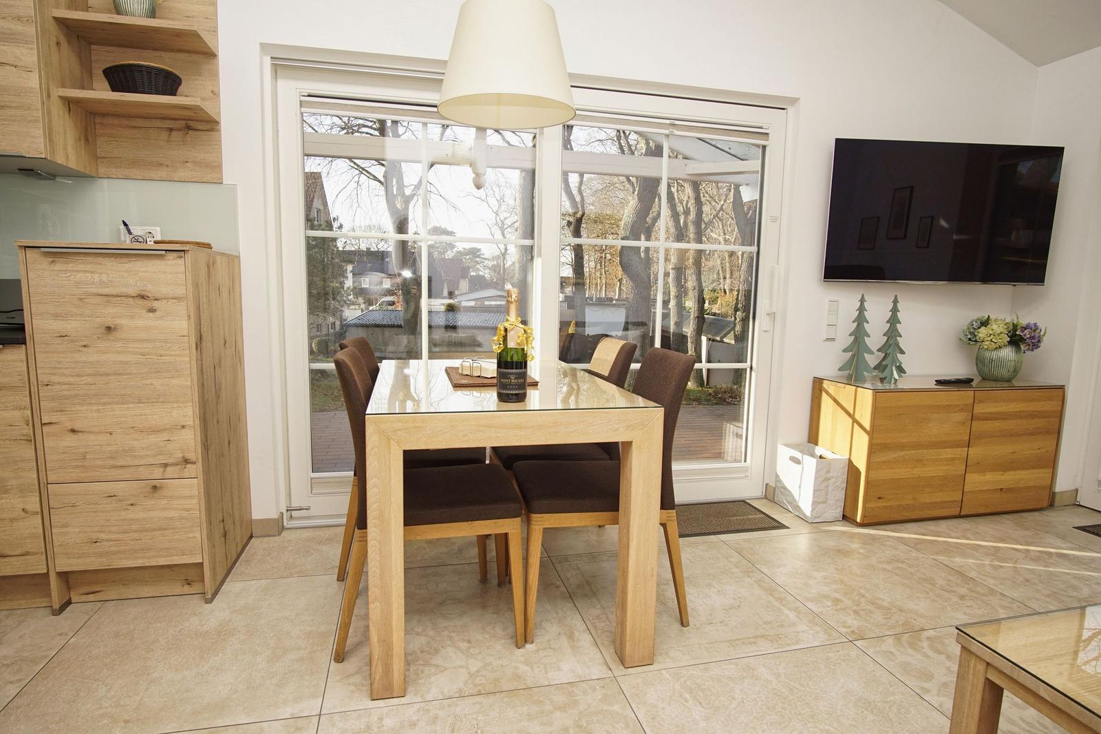 Esszimmer mit Holztisch, Stühlen und Blick auf Außenbereich.