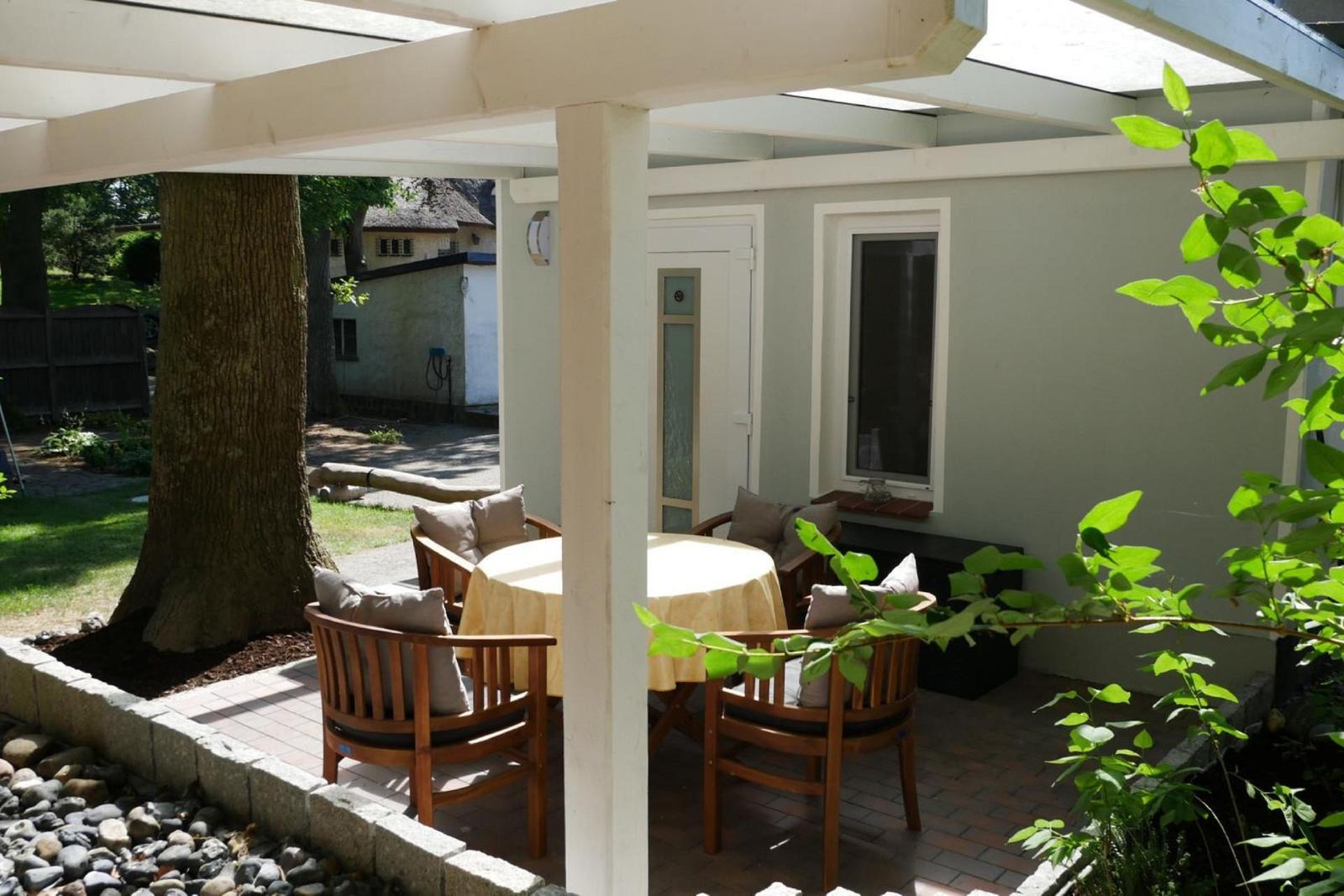 Terrasse mit Tisch, Stühlen und Sonnenschutz unter einem weißen Pavillon.