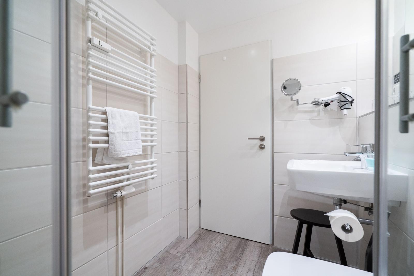 Badezimmer mit Handtuchwärmer, Waschbecken und Spiegel