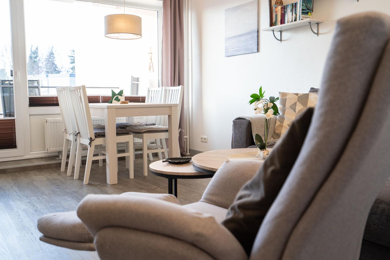 Ein Wohn- und Essbereich mit Sofa, Tisch und Stühlen sowie Fenster und Wandregal.