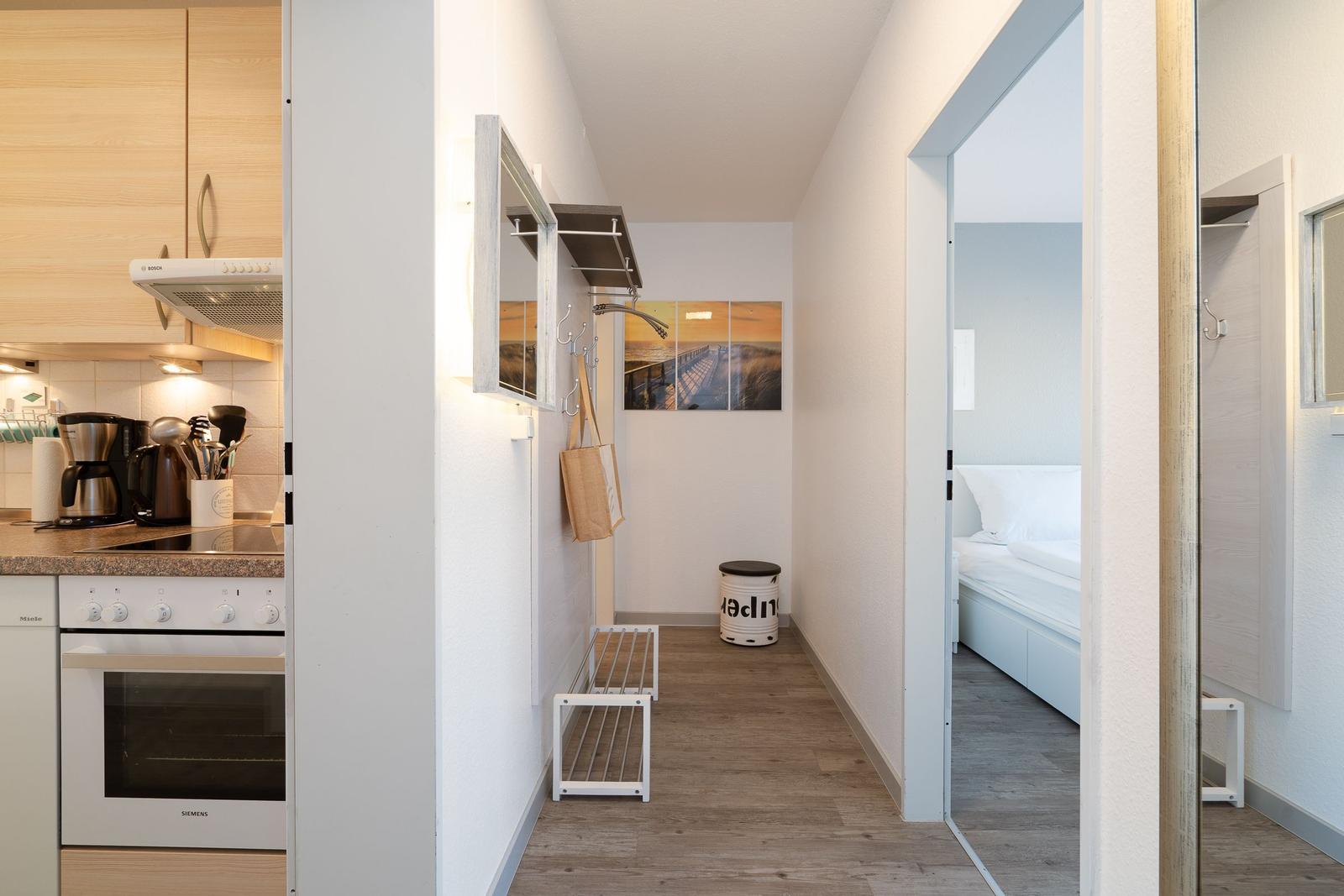 Küche mit Kochfeld und Ofen, Flur mit Wandbild und Schlafzimmer mit Bett