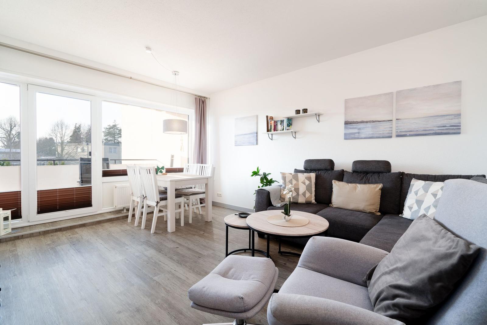 Wohn- und Essbereich mit Sofa, Esstisch und Balkontür.