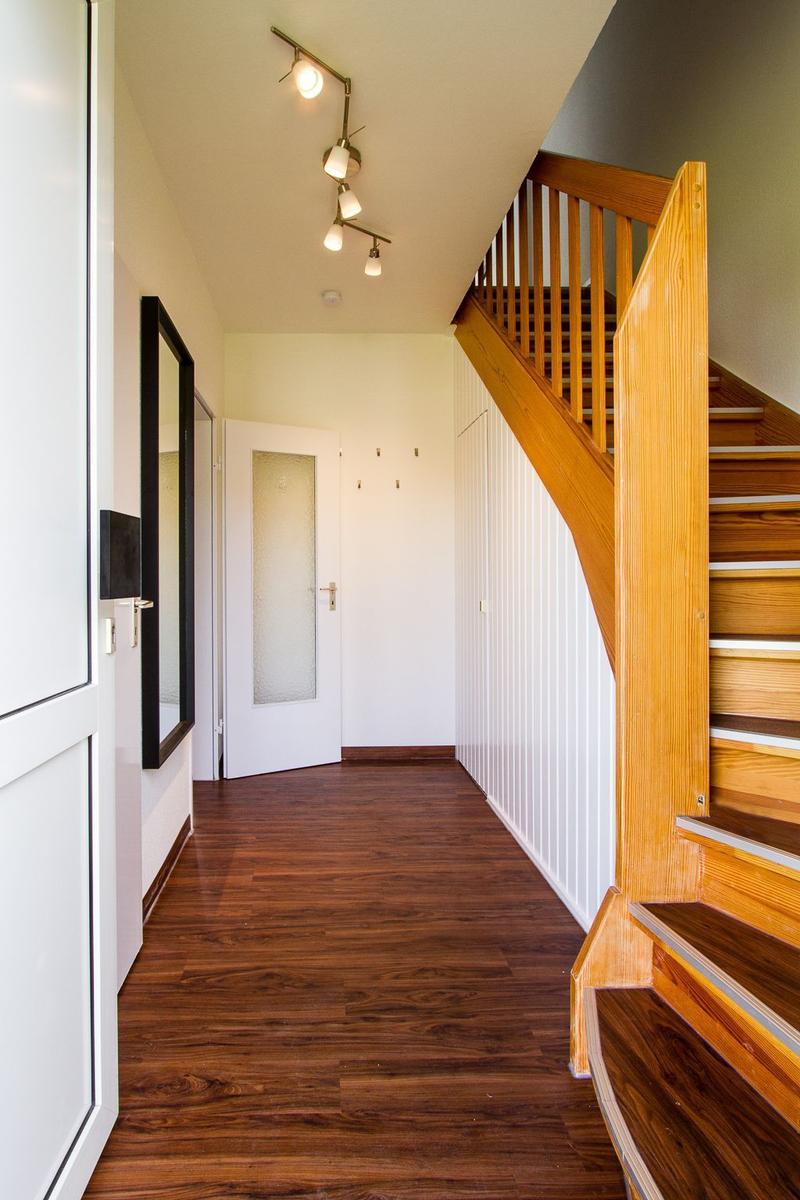 Flur mit Holztreppe, dunklem Parkett und moderner Deckenbeleuchtung.