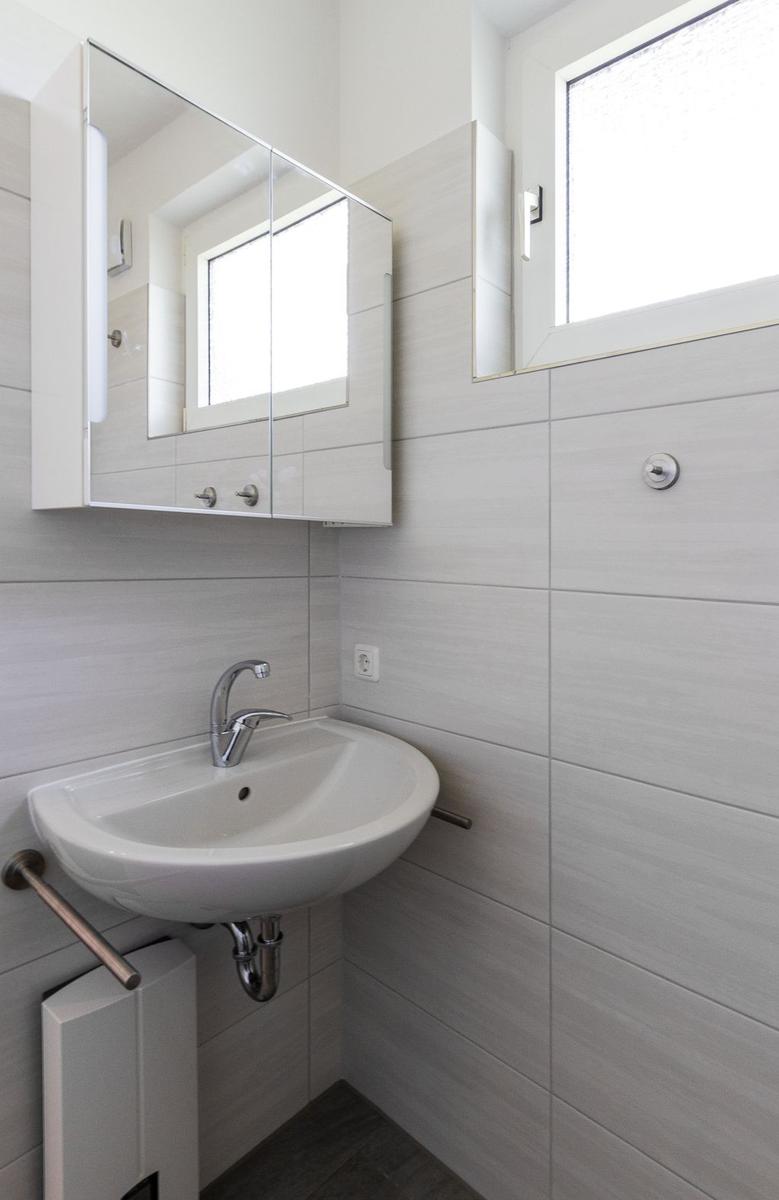 Badezimmer mit Waschbecken, Spiegelschrank und Fenster.