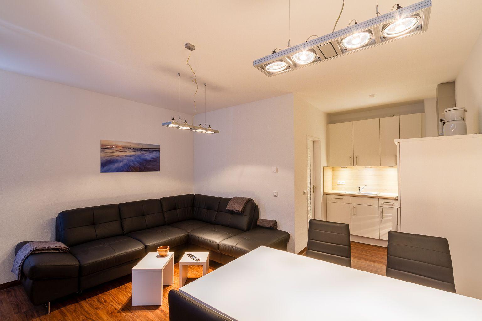 Wohn- und Essbereich mit Sofa, Tisch und Küchenbereich.