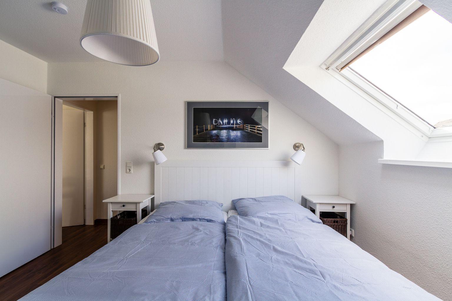 Schlafzimmer mit Doppelbett, zwei Nachttischen und Dachfenster.