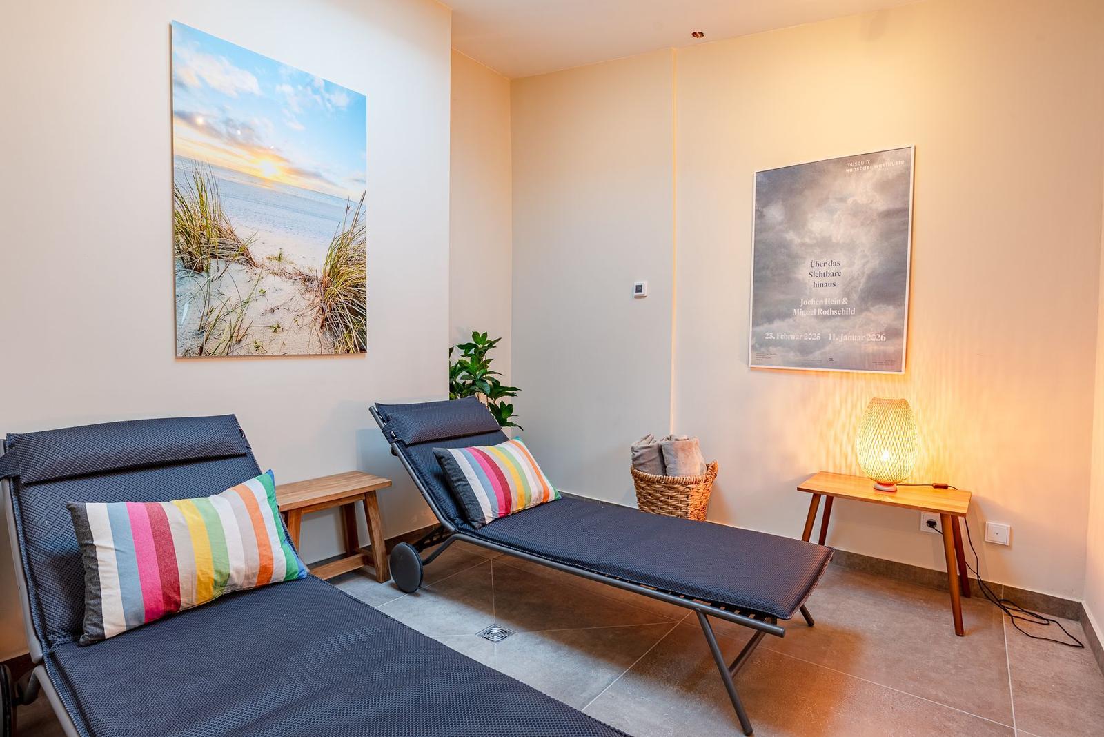 Zwei Liegestühle mit Kissen, Wandbilder und eine Lampe.