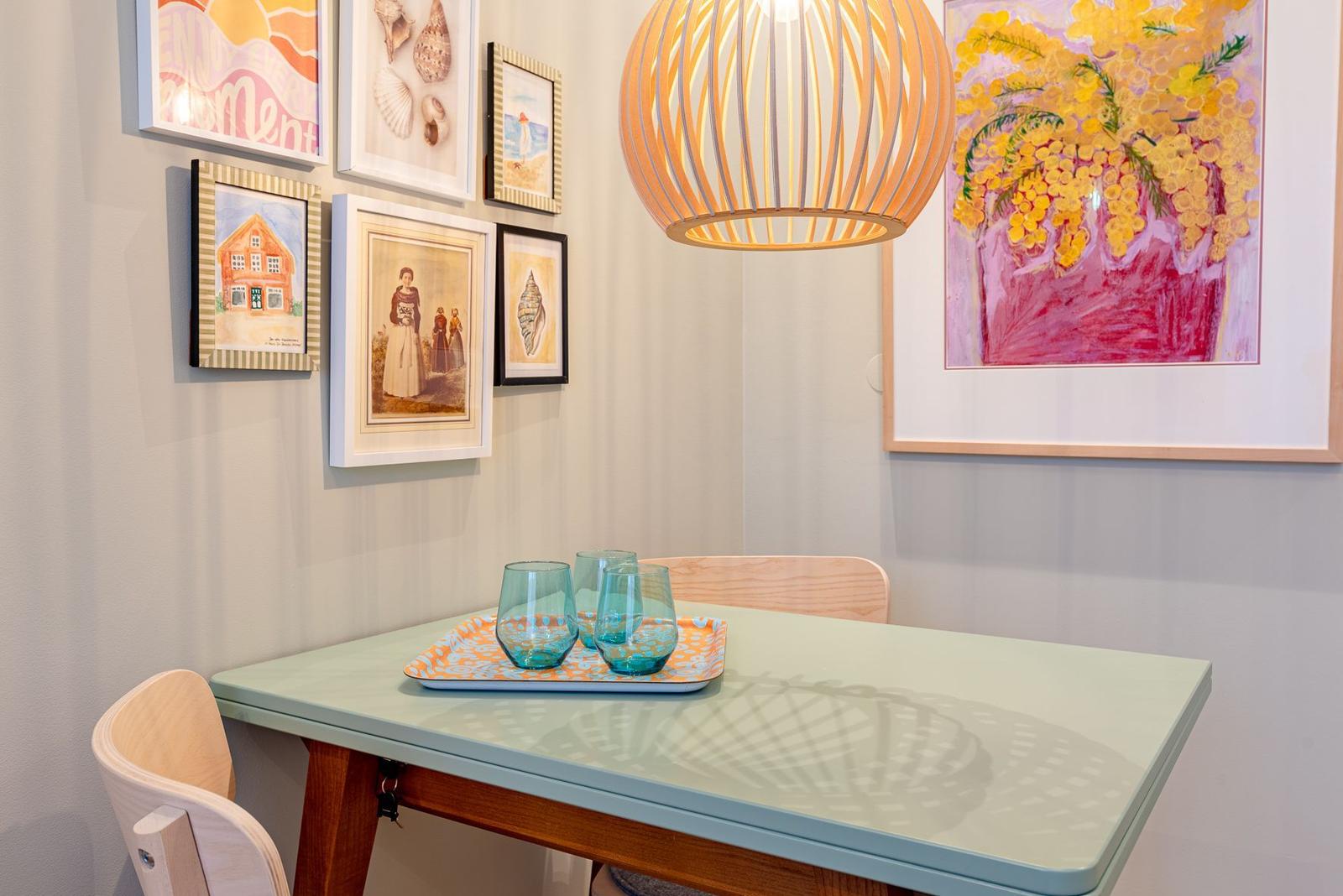 Esstisch mit zwei Stühlen, Wandbilder und einer Lampe über dem Tisch.