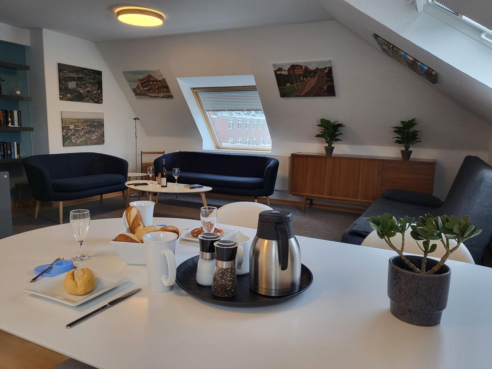 Wohnbereich mit Schlafsofa, Couch und Essplatz. Dachfenster, Bilder und Pflanzen.