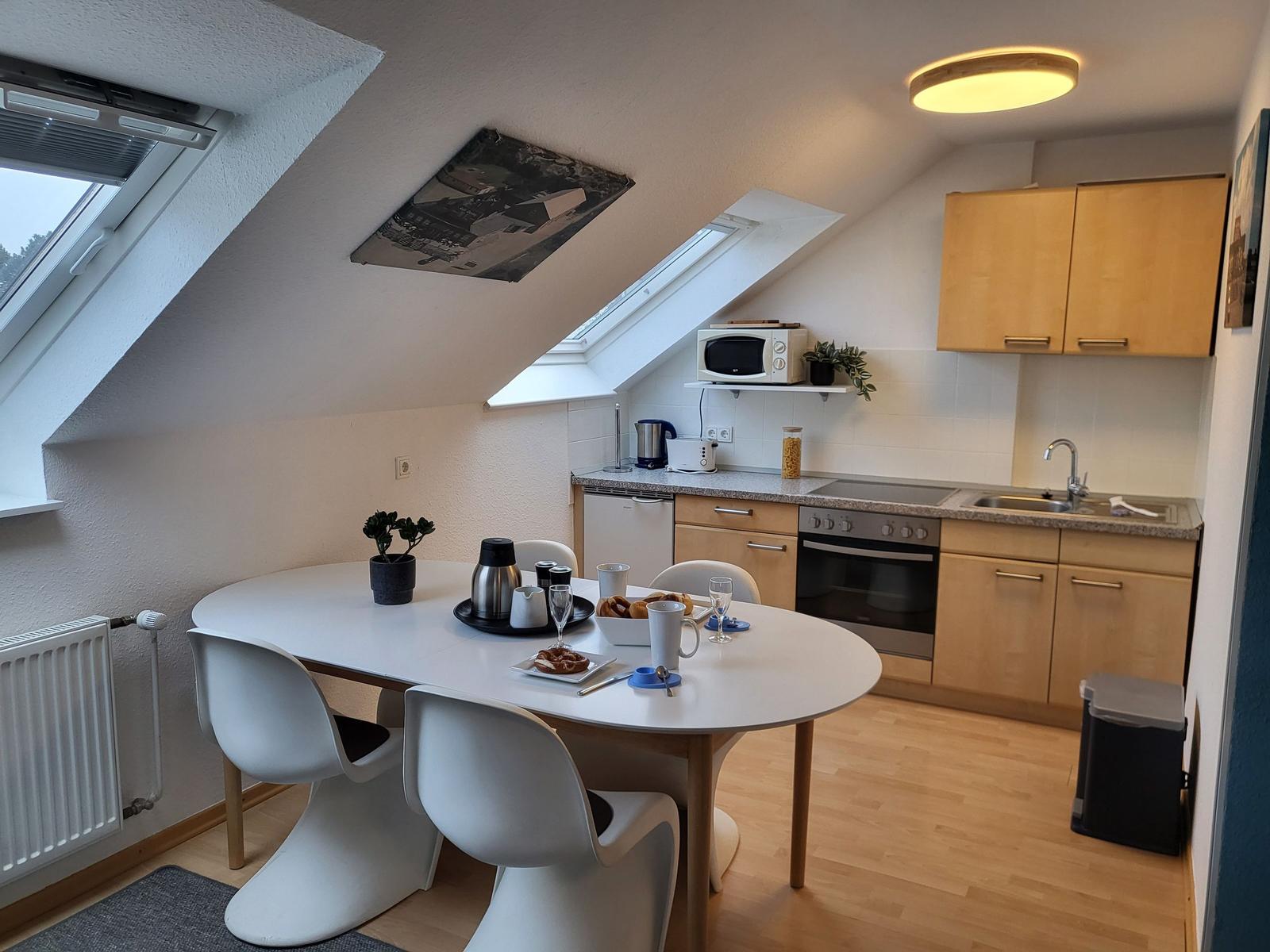 Küche mit Esstisch, zwei Dachfenstern und hellen Holzmöbeln.