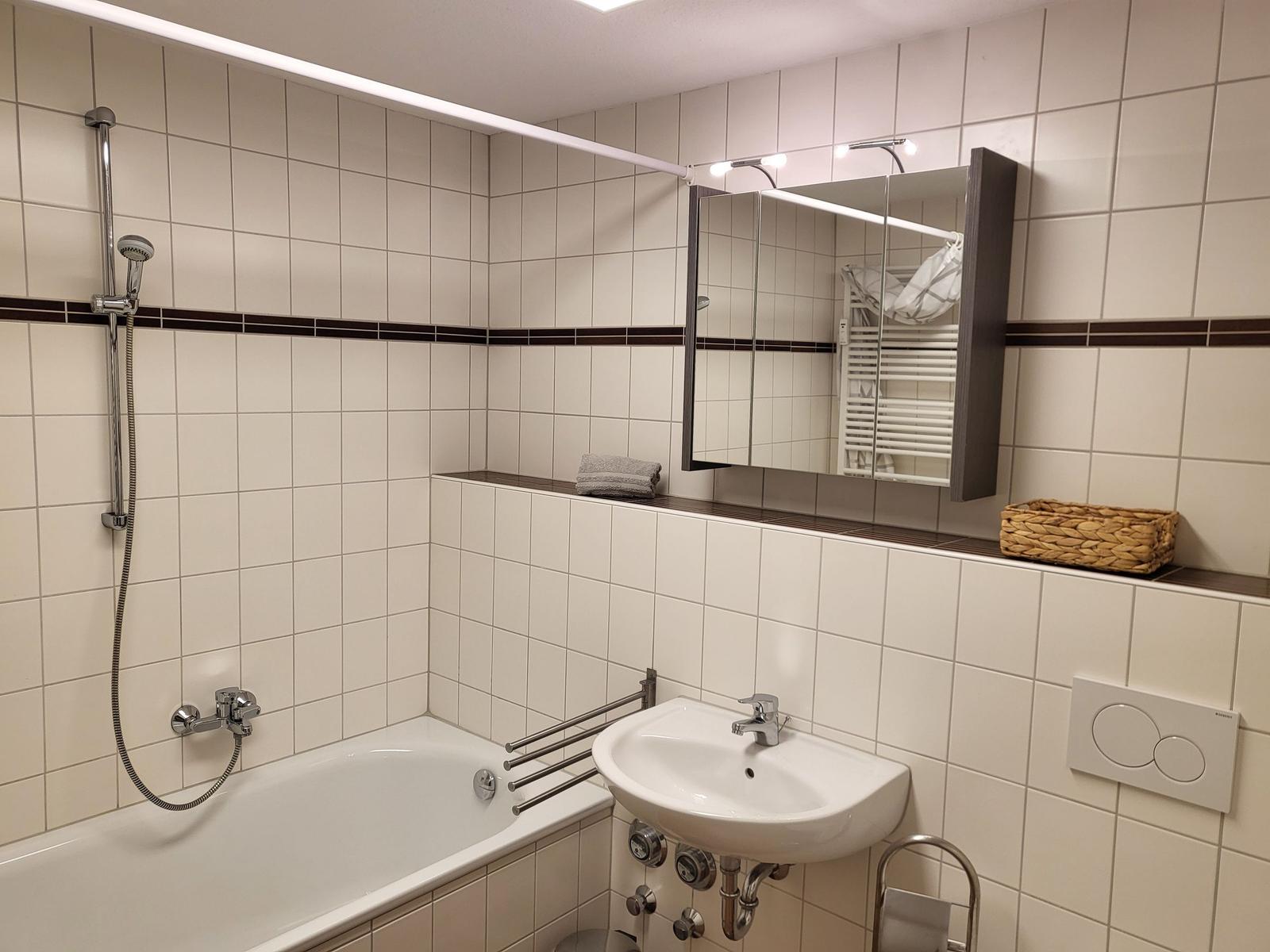 Badezimmer mit Badewanne, Dusche, Waschbecken und Spiegelschrank.