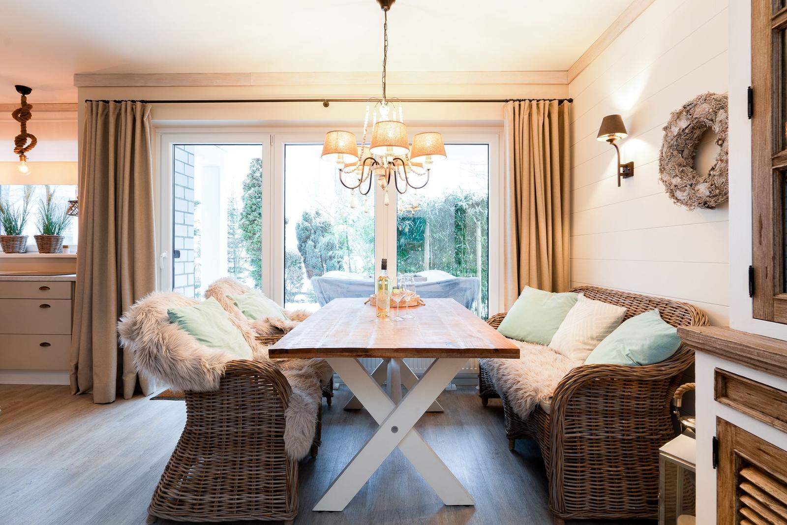 Essbereich mit wicker Sitzgruppe, Holztisch und Blick auf Garten.