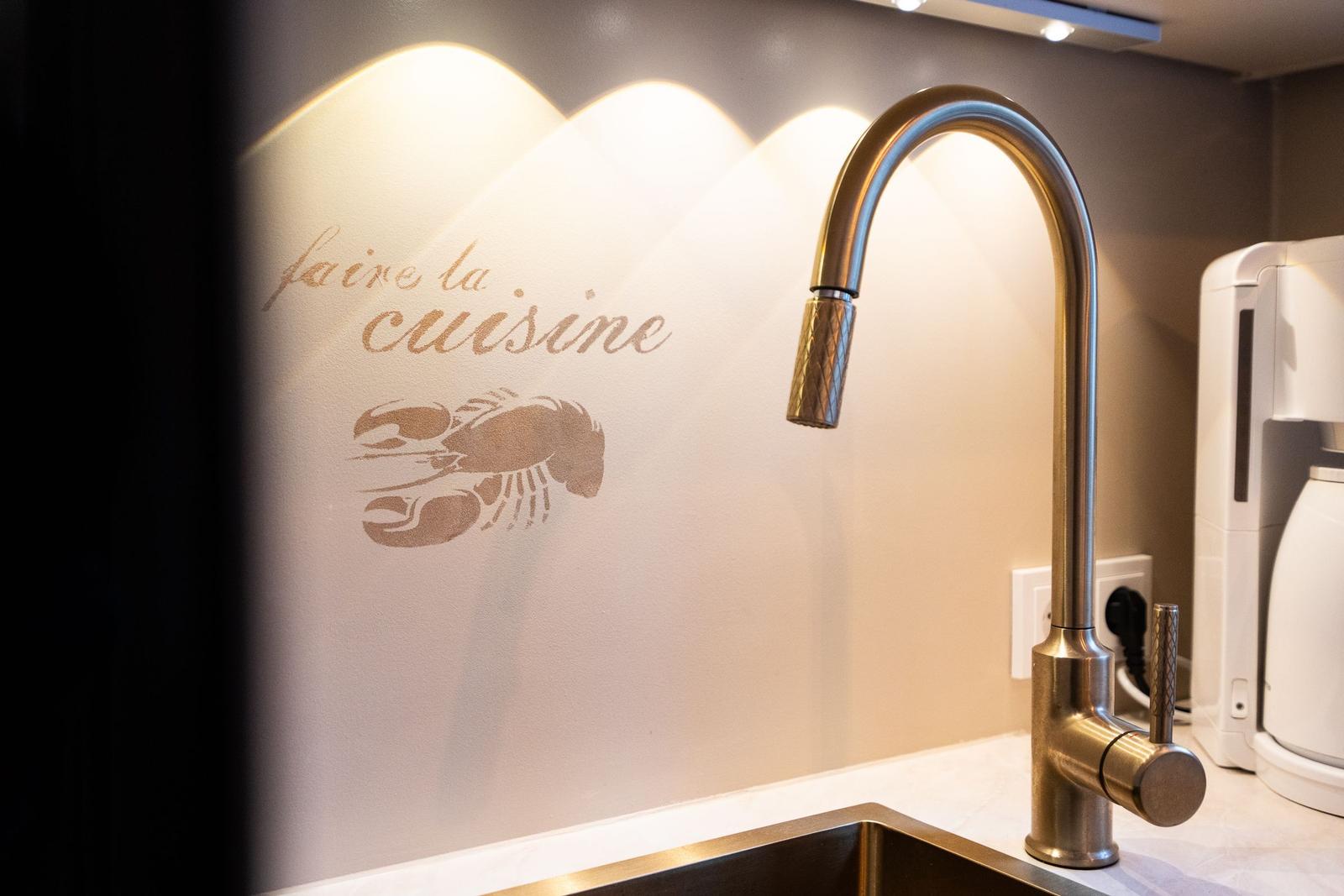 Küchenzeile mit Wasserhahn und Wanddekoration mit Krabbe und Schriftzug.