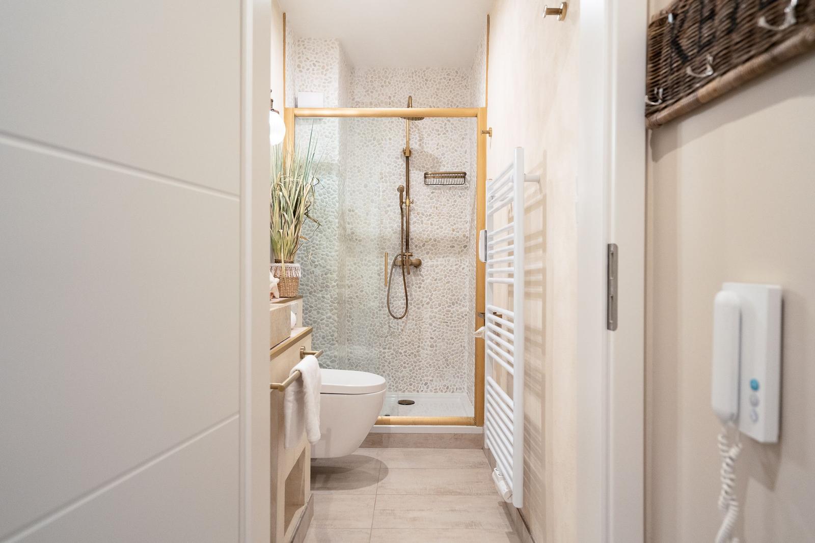 Badezimmer mit Dusche, Toilette und Handtuchheizung.