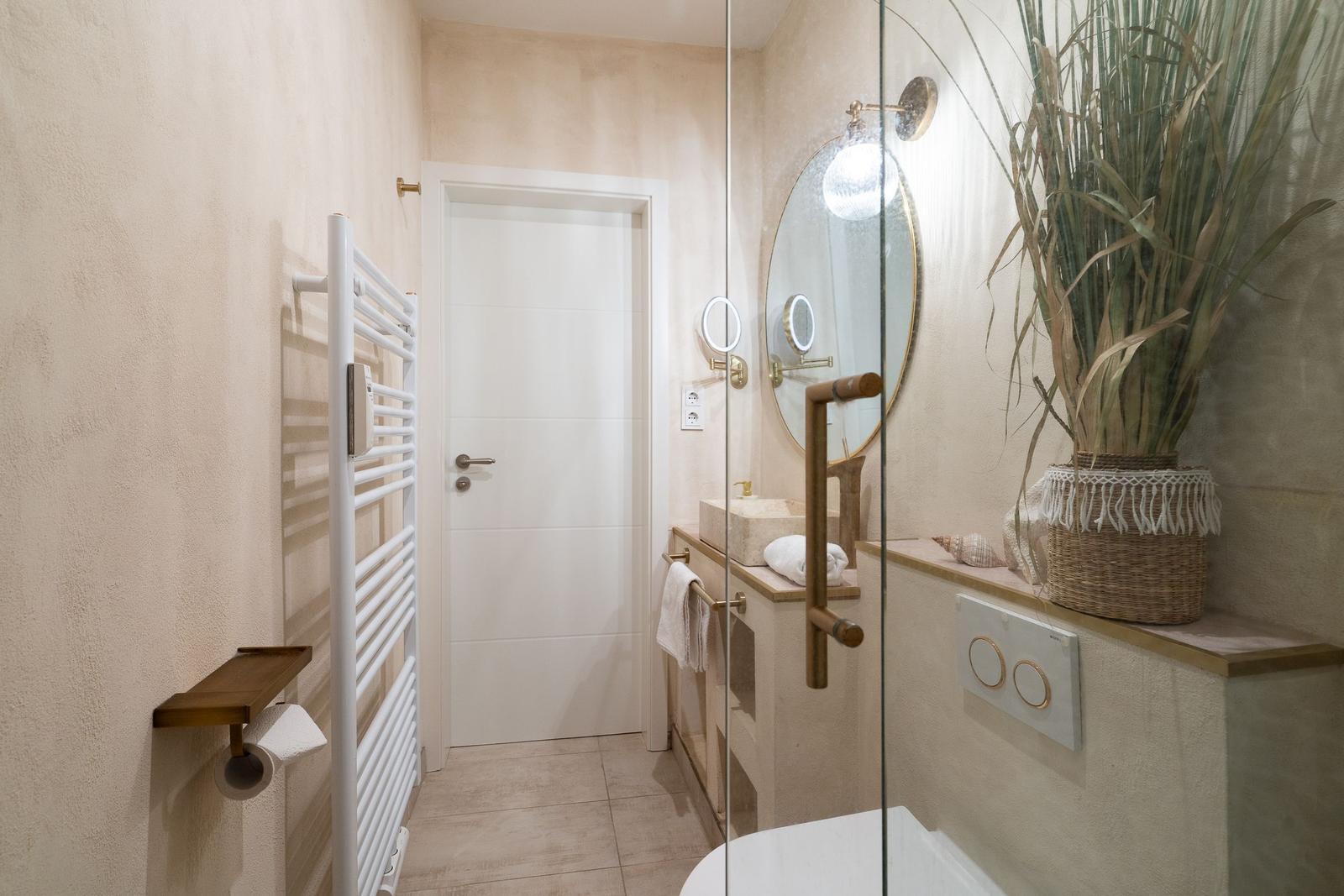 Bad mit Dusche, Waschtisch und Heizung. Große Pflanze auf der Arbeitsfläche.