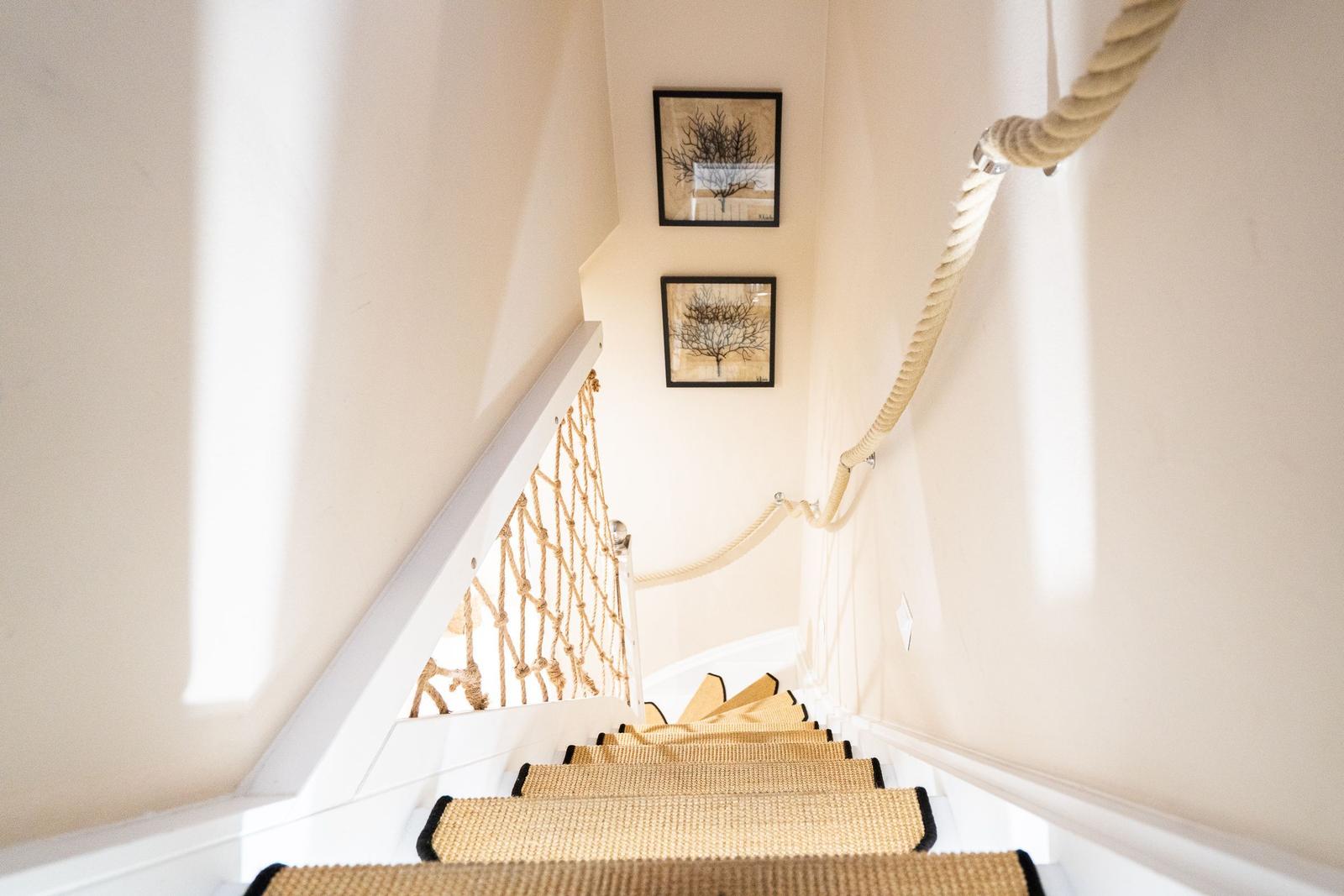 Treppe mit Seilgeländer und Teppichstufen, Wandbilder mit Bäumen