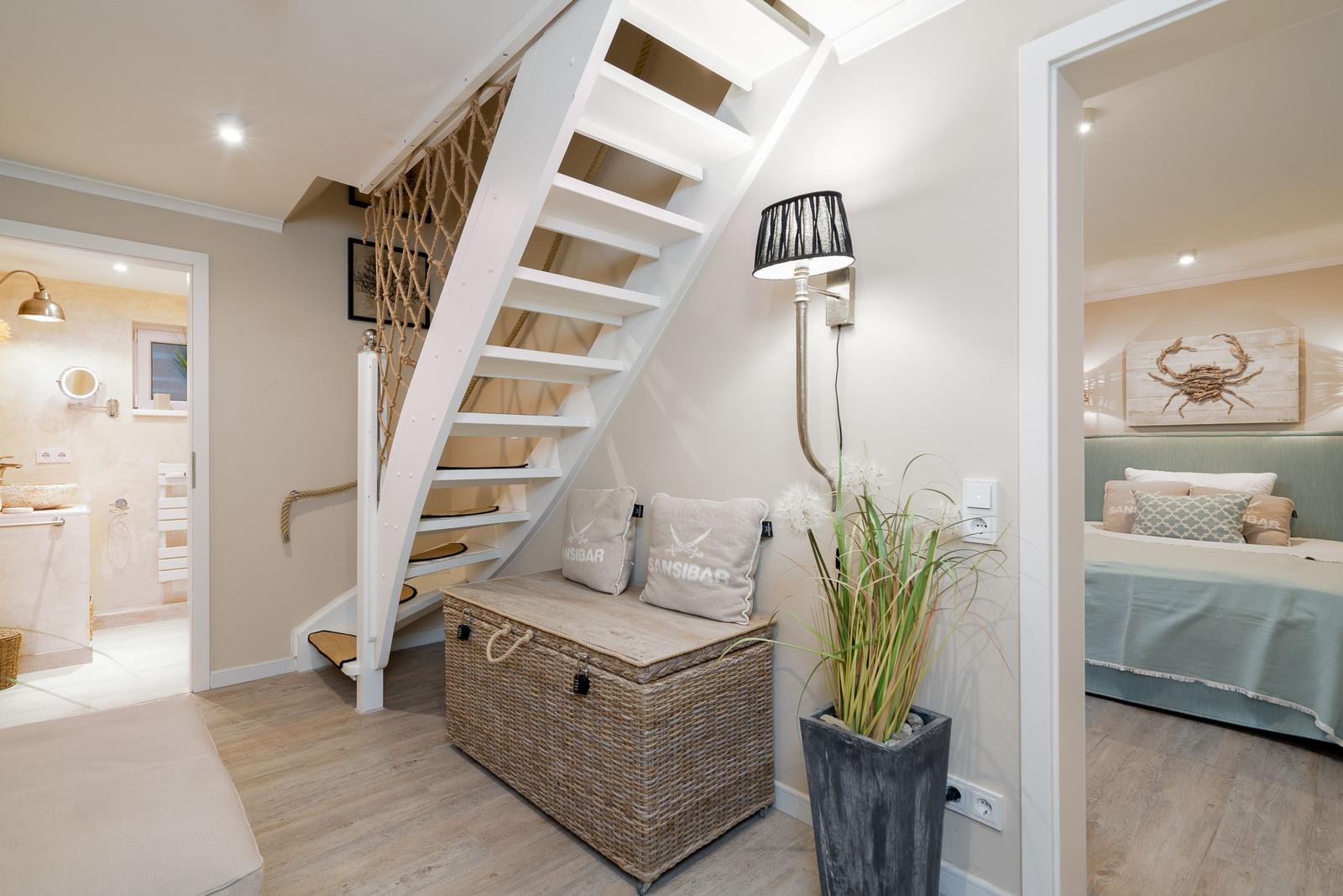Treppenhaus mit Korb und Pflanze. Im Hintergrund Bad und Schlafzimmer.