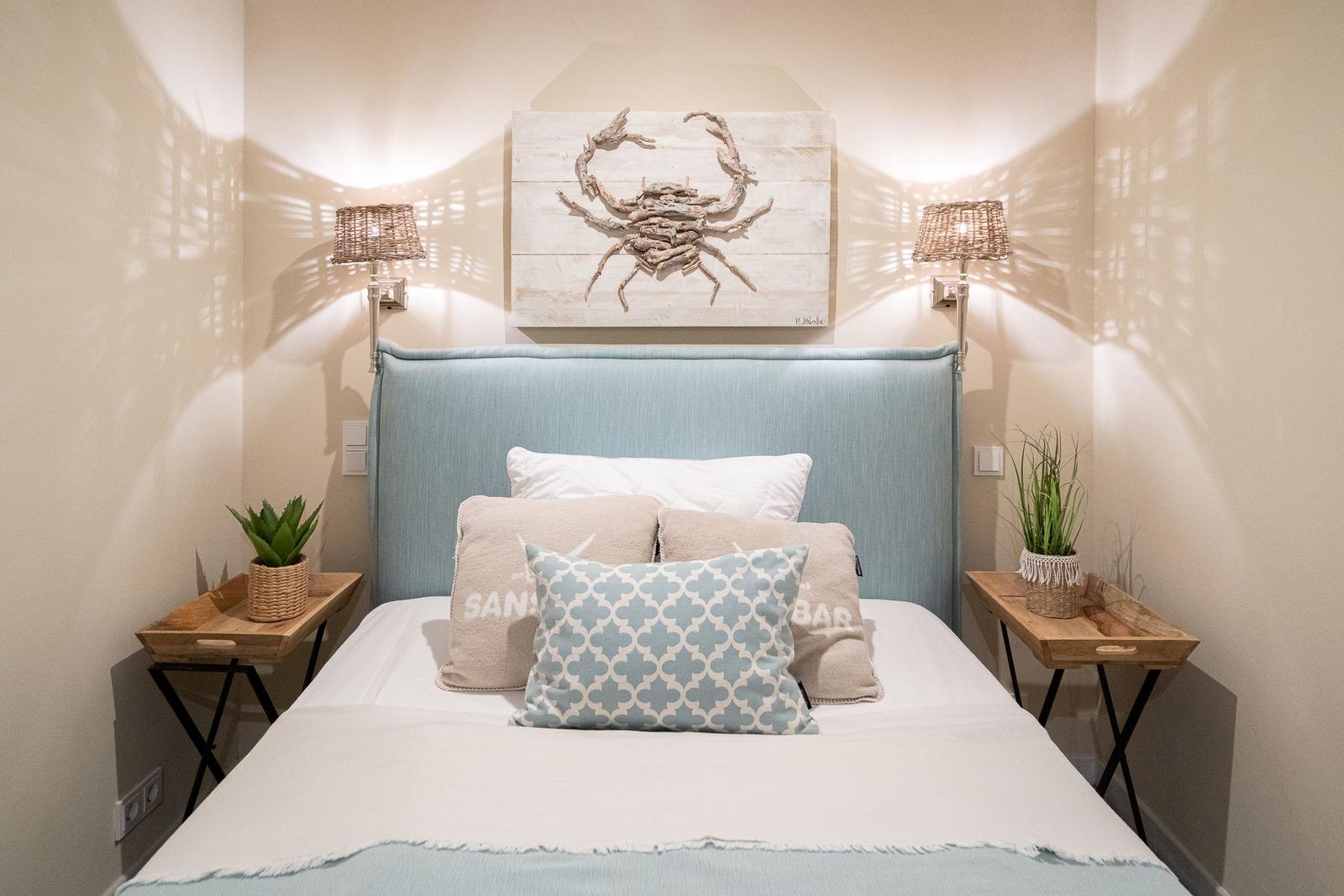 Schlafzimmer mit Bett, zwei Nachttischen und Wanddekoration.