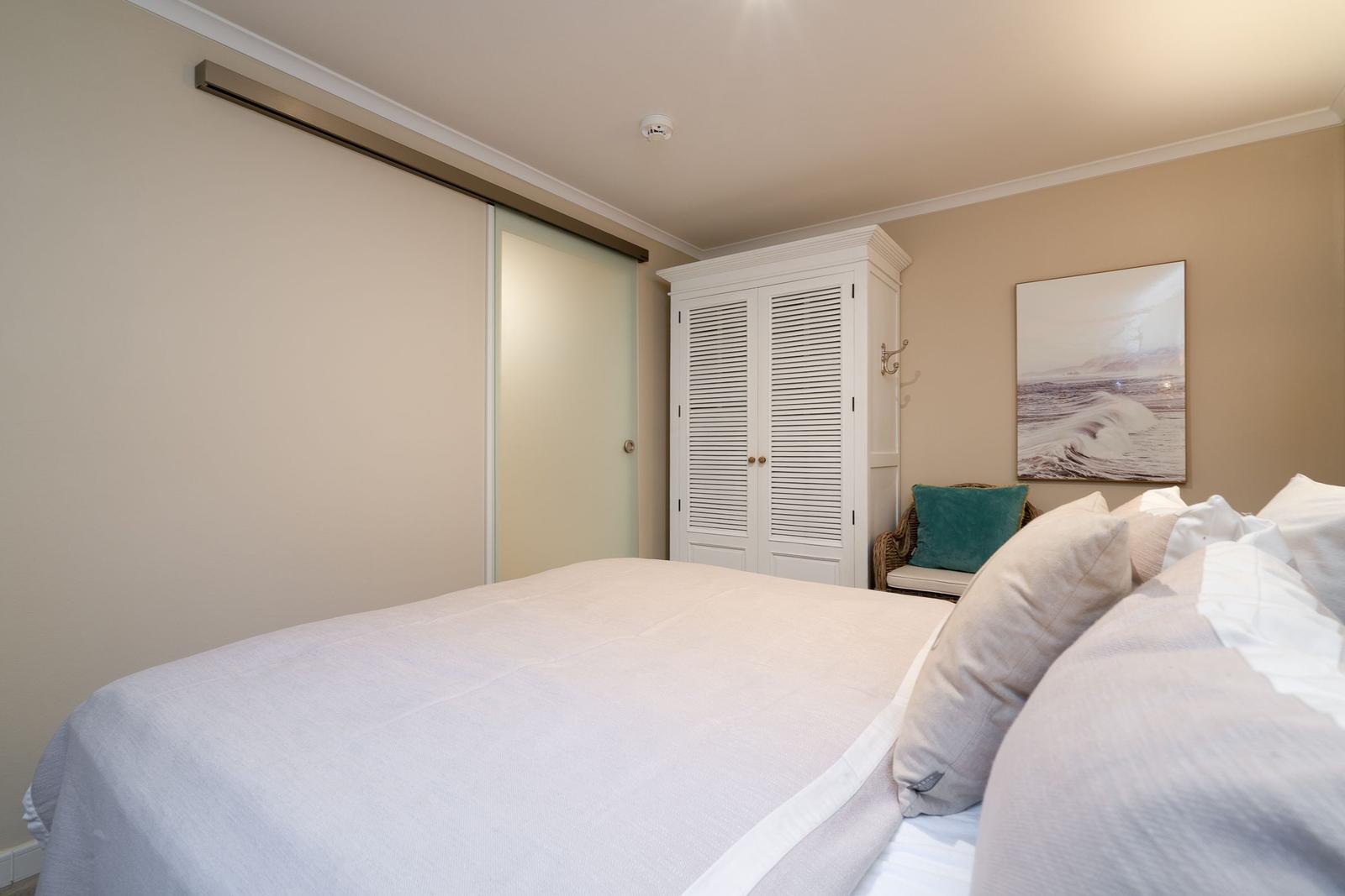 Schlafzimmer mit Bett, Kleiderschrank und Wandbild. Schlupftür und Hängeregler sind sichtbar.