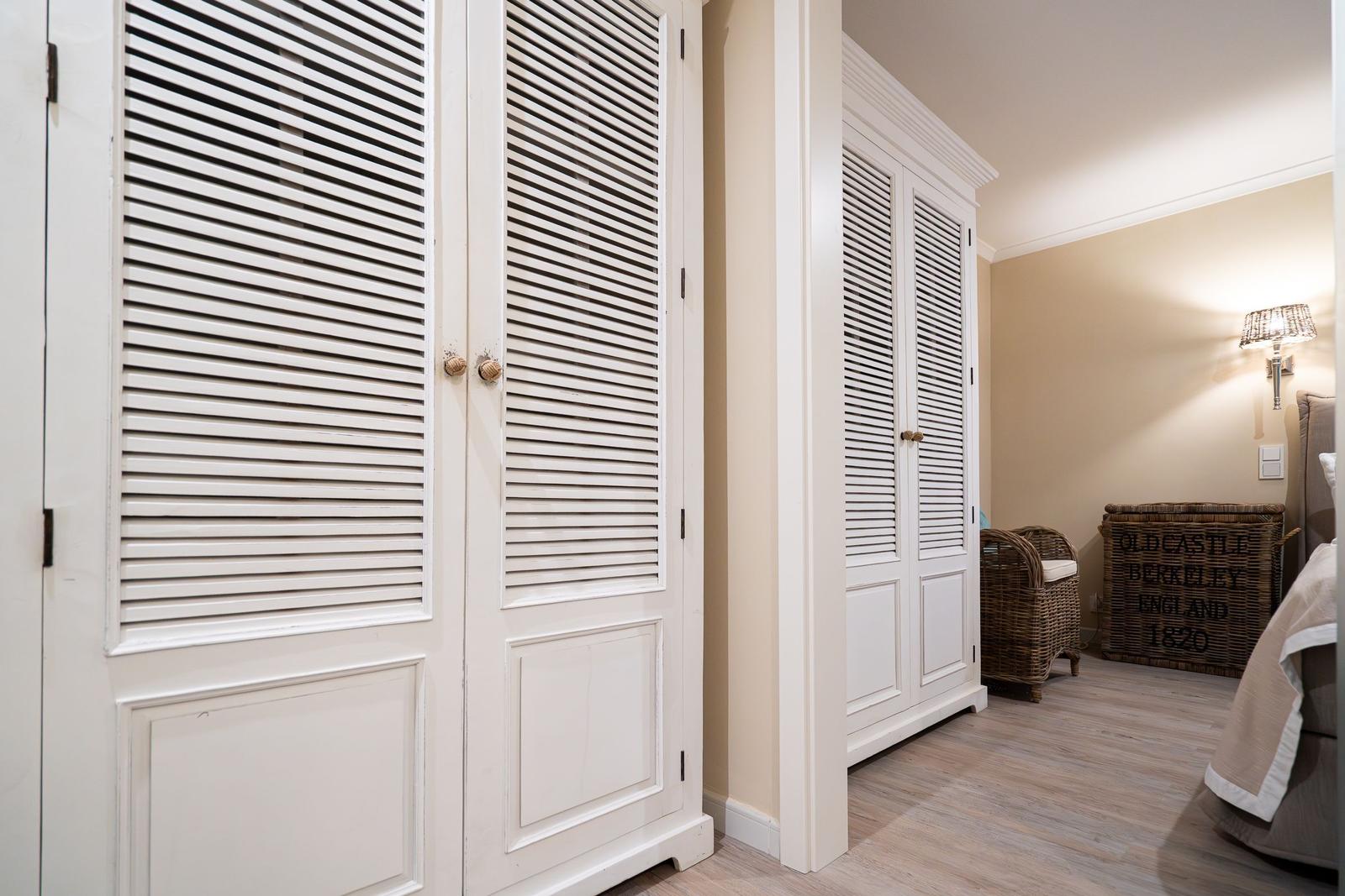 Zimmer mit weißen Schiebetüren, Wickerstuhl und Wandlampe