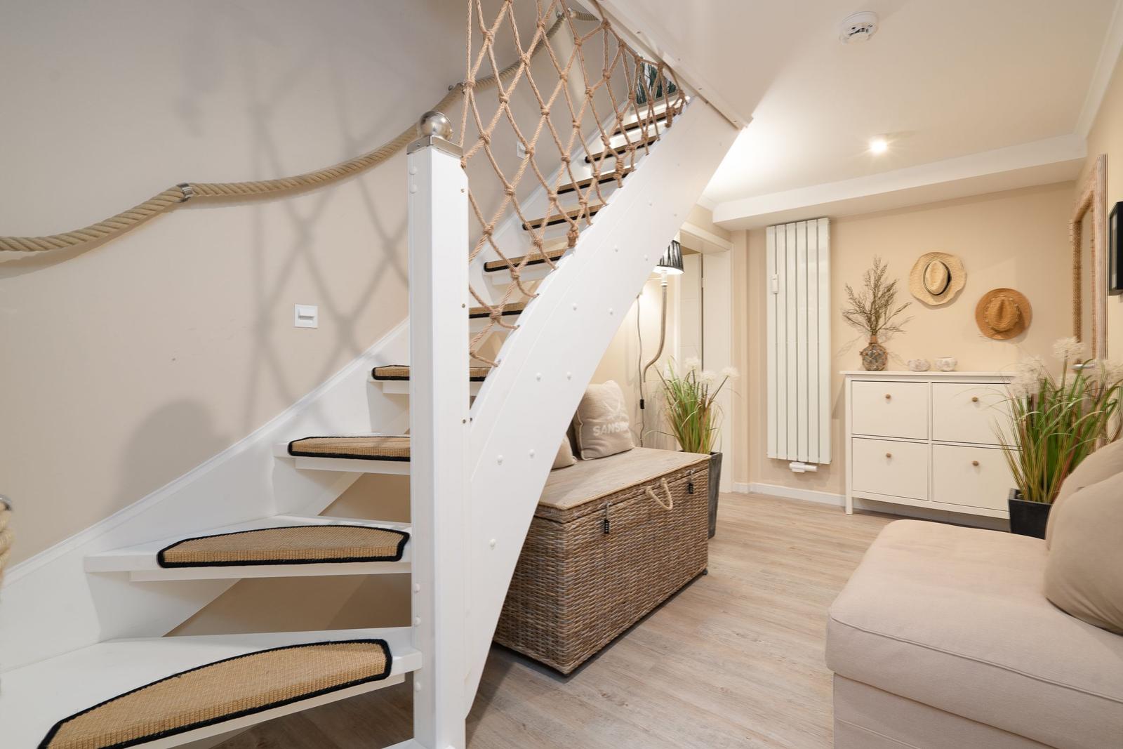 Treppenhaus mit Seilgeländer und Sitzbank unter der Treppe.