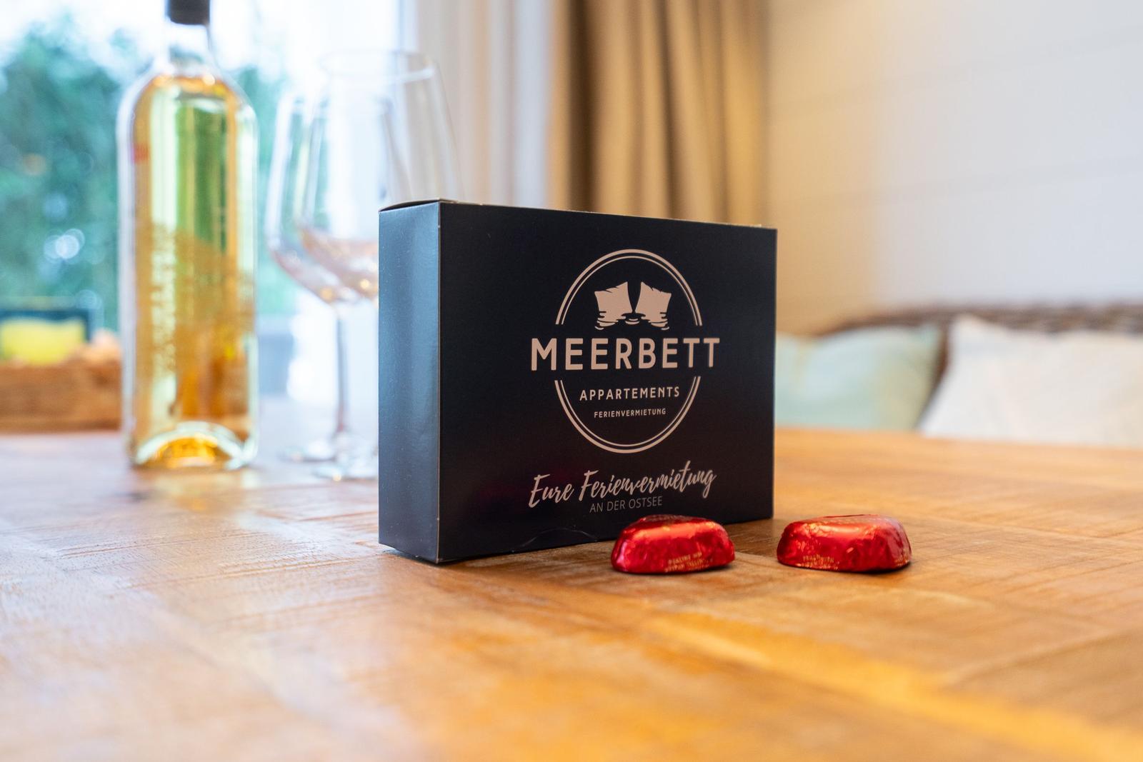 Auf dem Tisch steht eine Schachtel mit Schokolade und eine Flasche Wein.