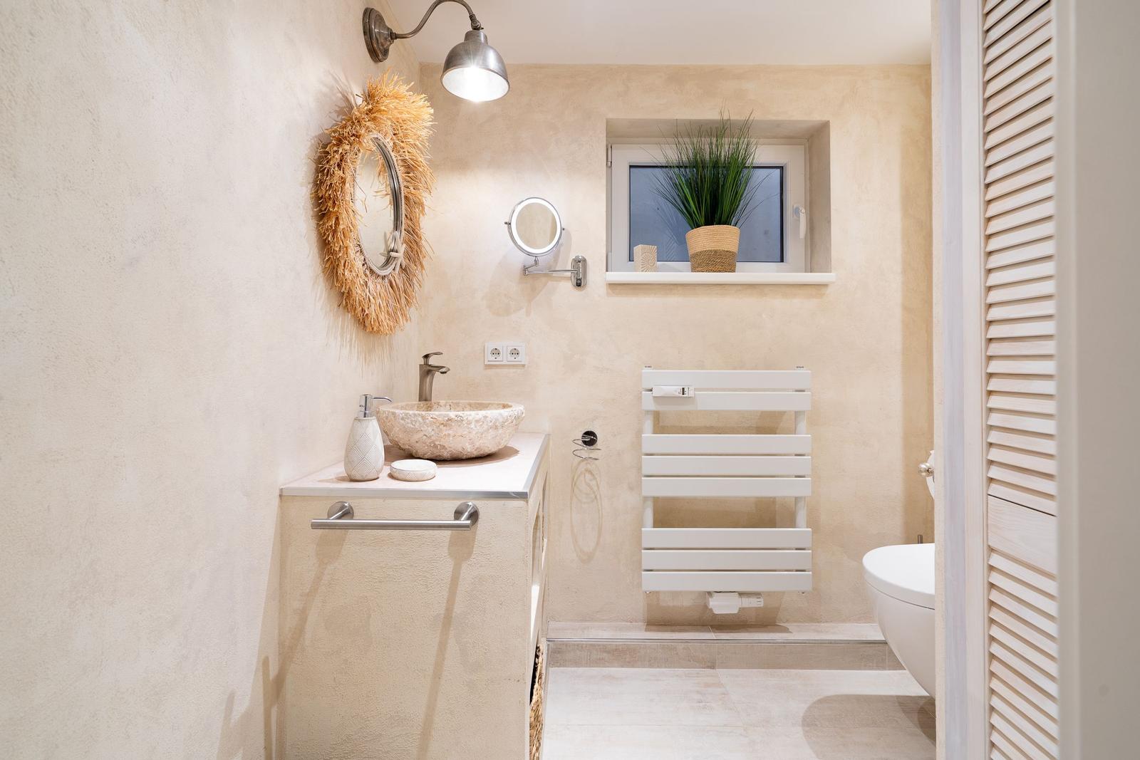 Bad mit Waschbecken, Spiegel, Heizkörper und Fenster