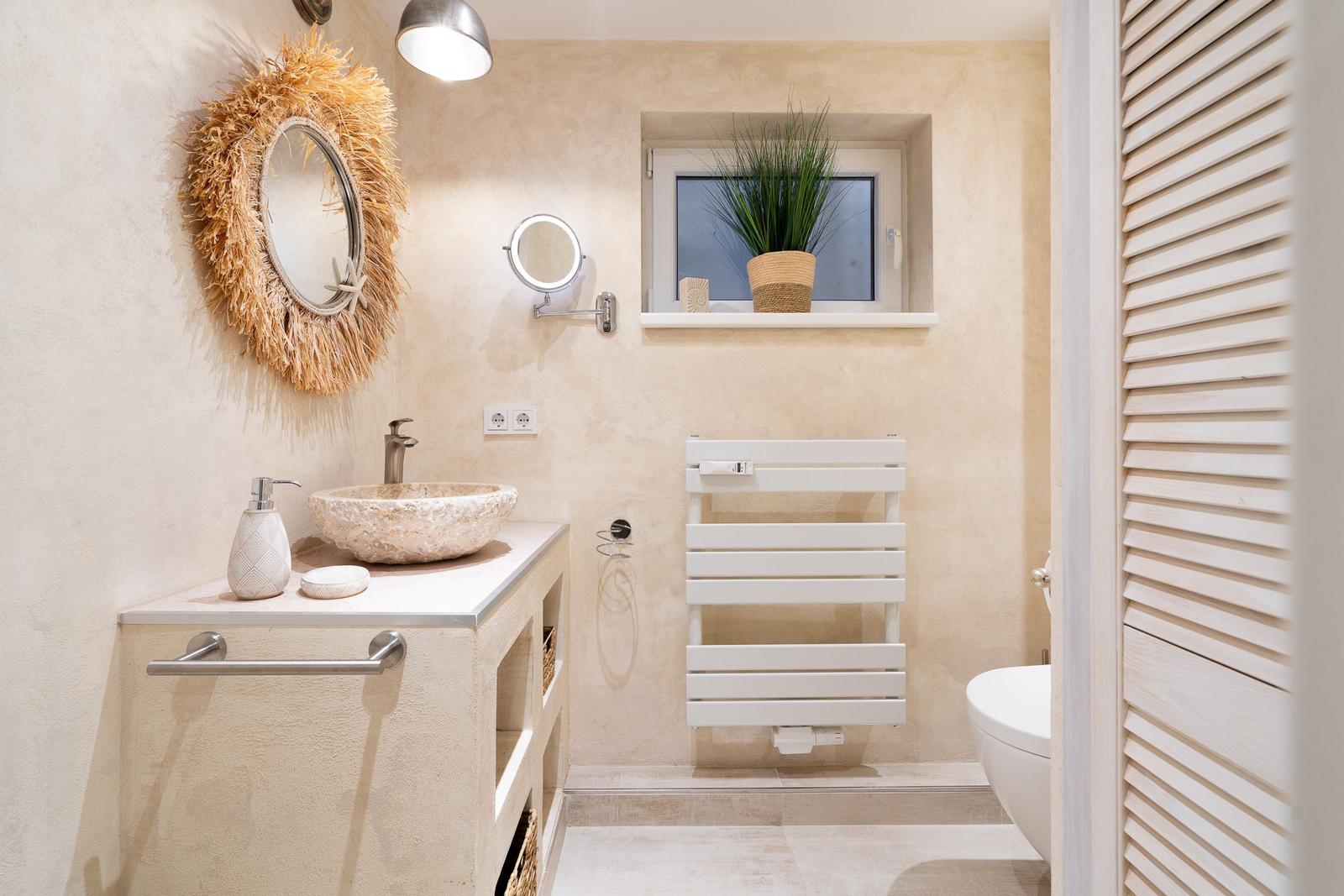 Badezimmer mit Waschbecken, Spiegel, Heizkörper und Toilette.