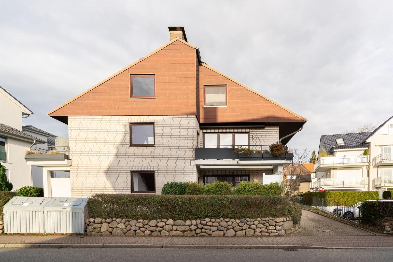 Modernes Haus mit Balkon und Steinmauer. Wohnhaus in ruhiger Wohngegend.