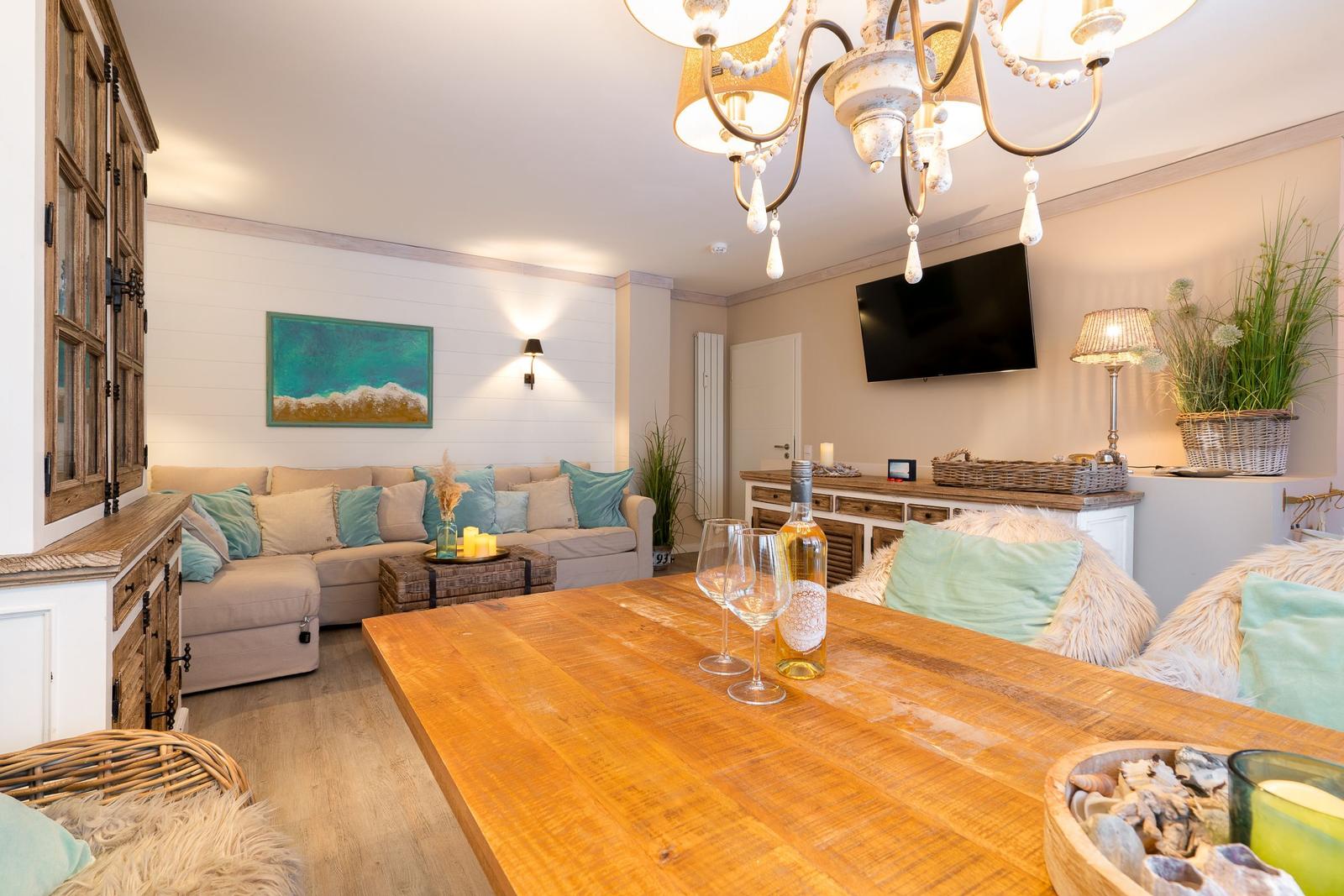 Wohn- und Essbereich mit Holztisch, Sofa und Fernseher an der Wand.