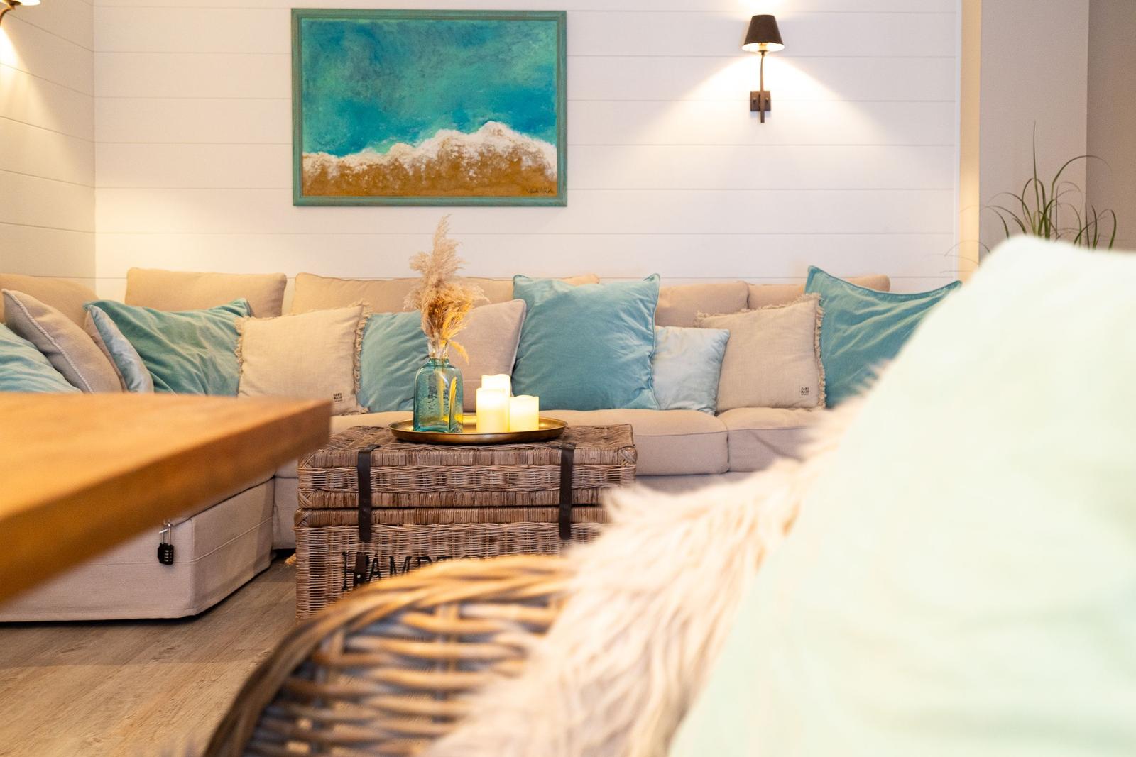 Ein Wohnzimmer mit Sofa, Kissen und einem Korbtablett mit Kerzen.