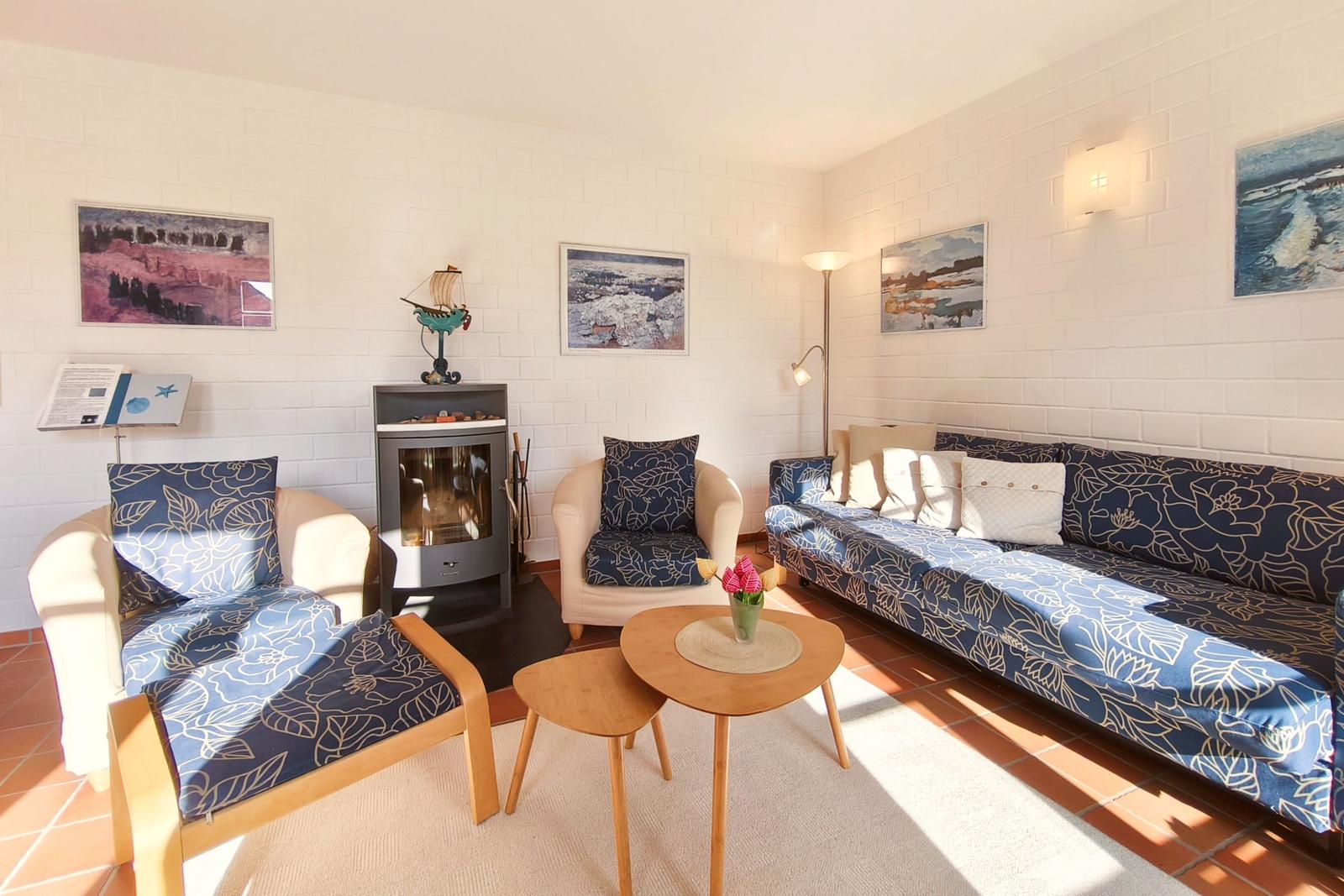 Wohnzimmer mit Sofa, Sessel und Kamin. Wandbilder und Holztisch.