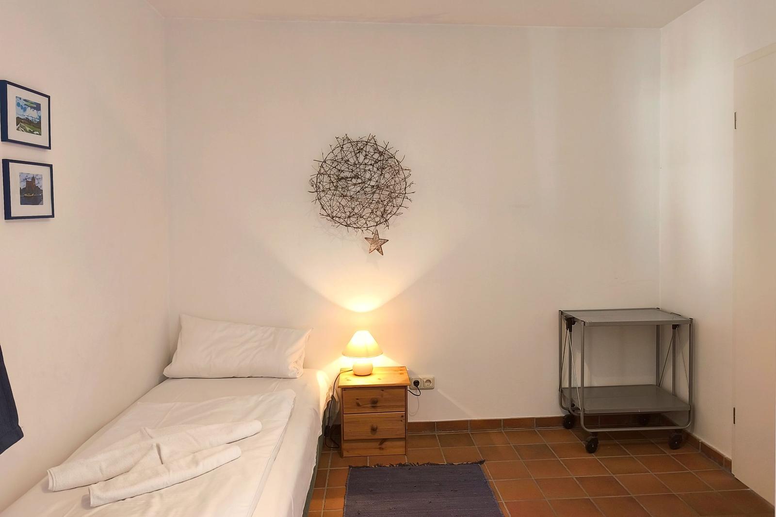 Ein Schlafzimmer mit Einzelbett, Nachttisch, Lampe und Wanddekoration.