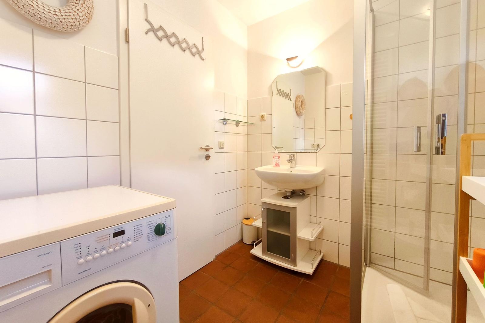 Badezimmer mit Waschmaschine, Dusche und Waschbecken