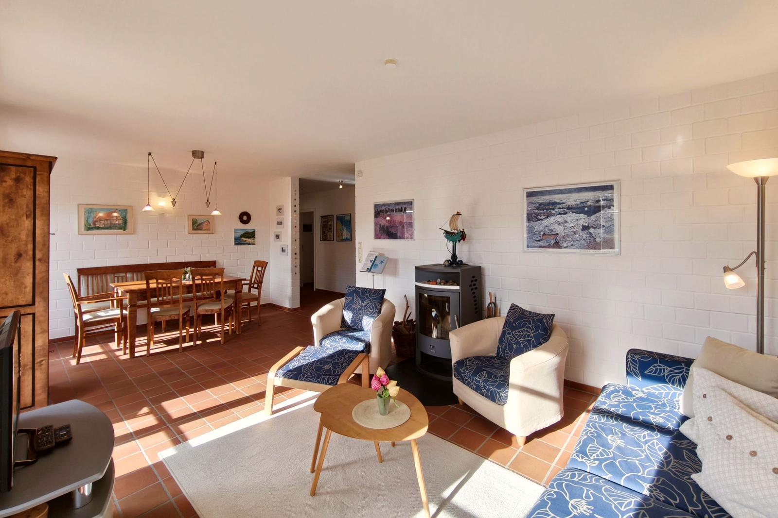 Wohn- und Essbereich mit Sitzgruppe, Esstisch und Kaminofen an weißer Ziegelwand.