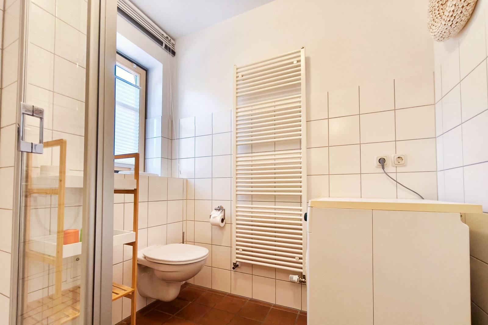 Badezimmer mit Dusche, WC und Heizkörper an der Wand.