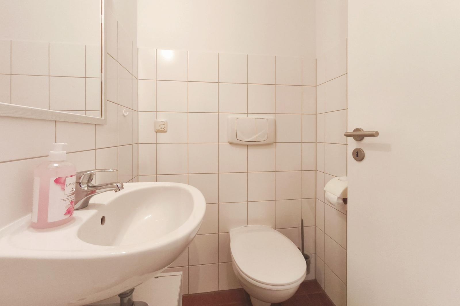 Badezimmer mit Waschbecken, Toilette und Spiegel an der Wand.