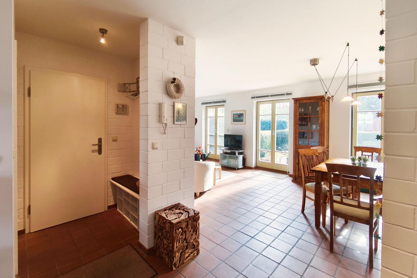 Eingangsbereich mit Wohn- und Essbereich, Holztisch, Stühle und TV.