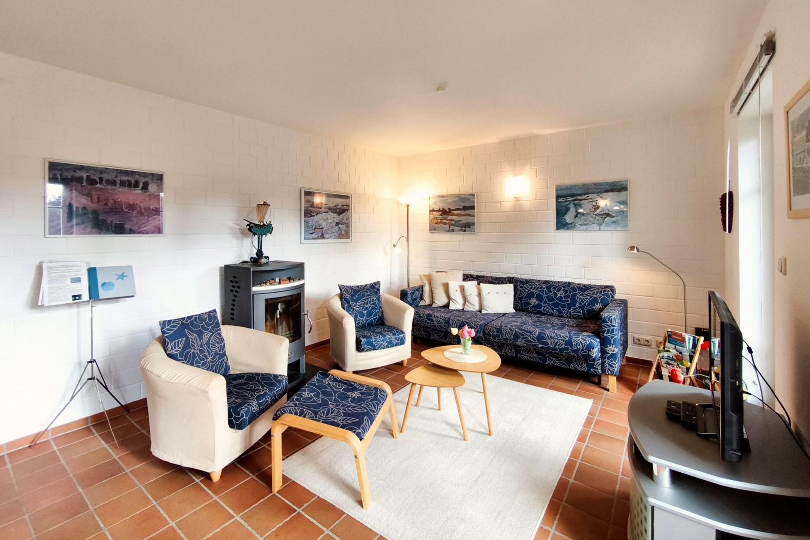 Wohnzimmer mit Sofa, zwei Sesseln, Kamin und Fernseher.