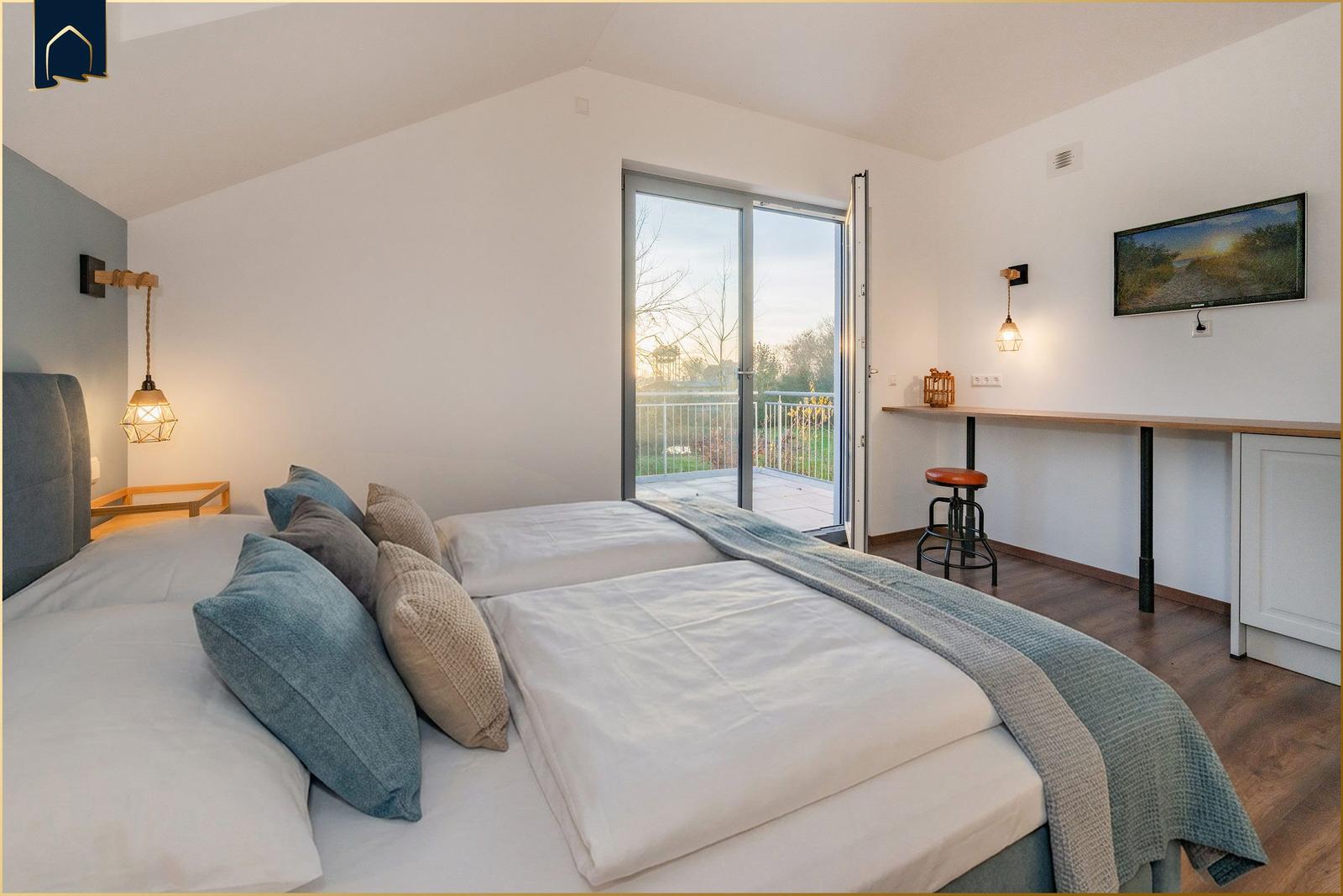 Schlafzimmer mit Doppelbett, Balkon und TV. Holzboden und moderne Beleuchtung.