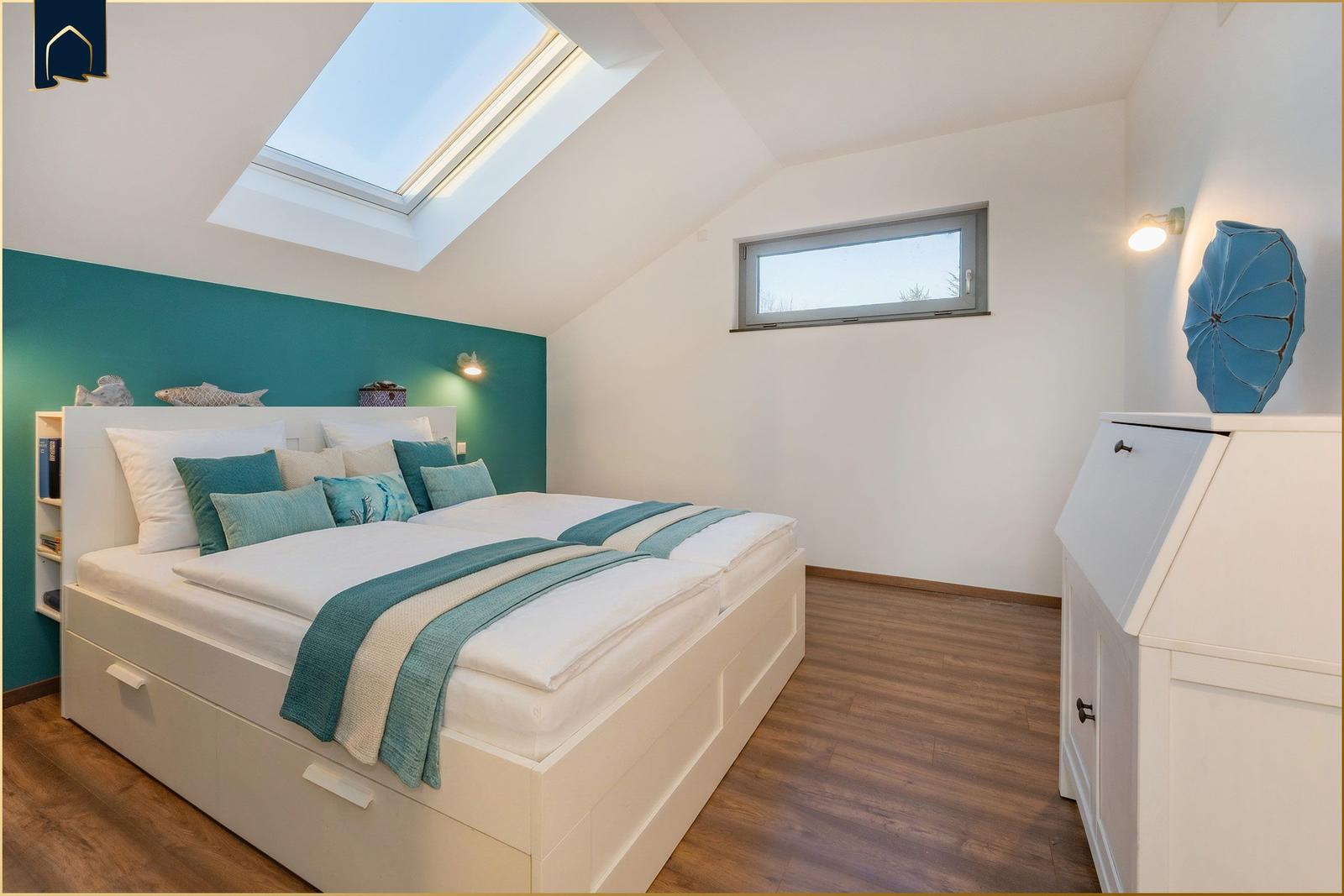 Schlafzimmer mit Dachschrägen, Dachfenster, Bett und Kleiderschrank.