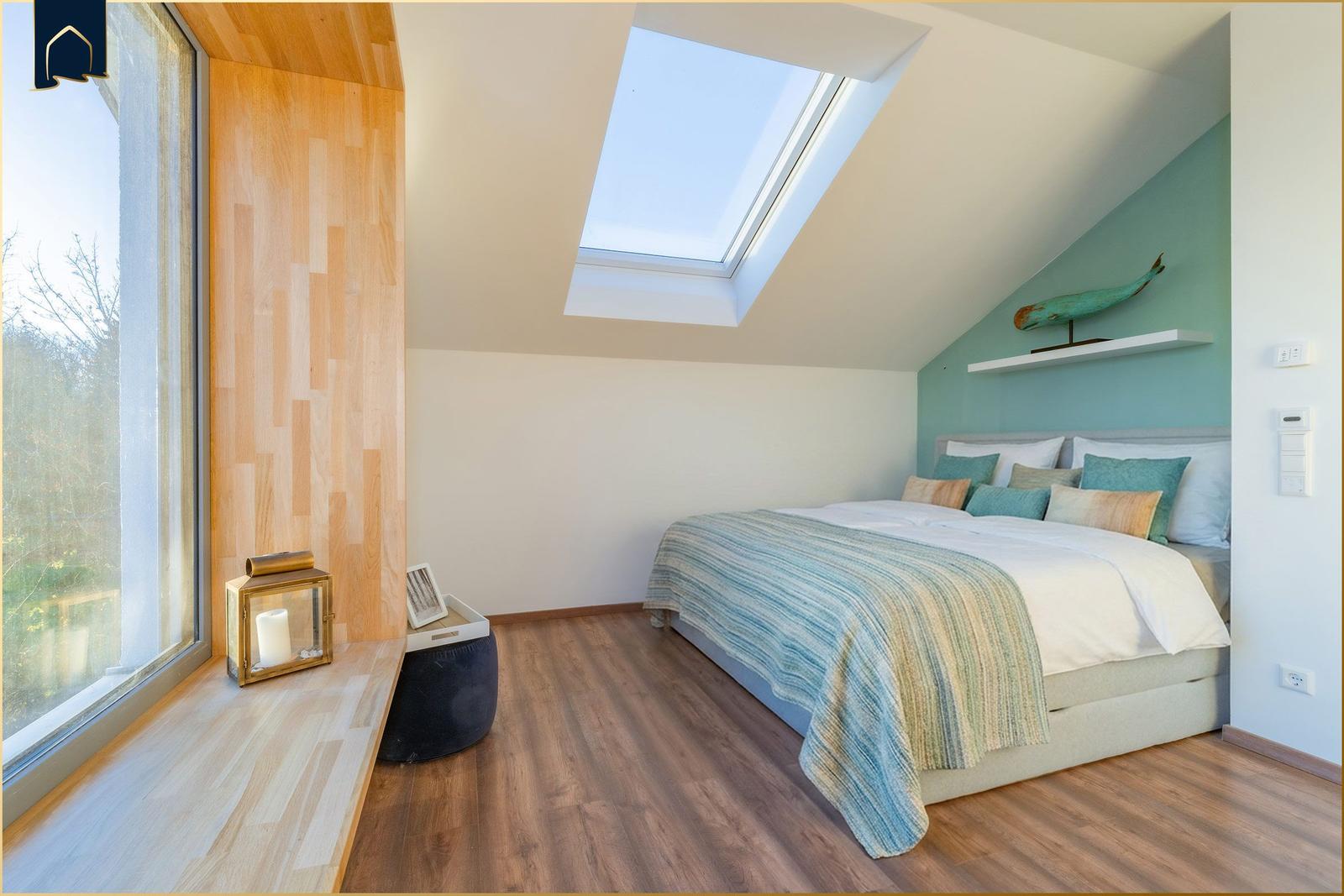 Schlafzimmer mit Dachschräge, Dachfenster, Bett und Holzboden.